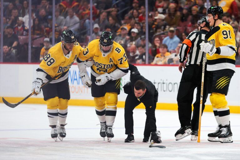 Boston Bruins defenseman Charlie McAvoy (73) is helped off the ice by right wing David Pastrnak (88) after an apparent injury against the Florida Panthers during the first period at Amerant Bank Arena.