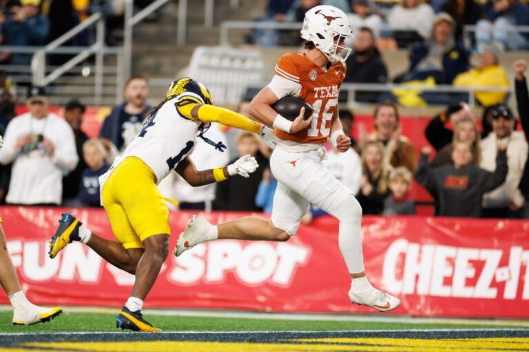 Texas Longhorns quarterback Arch Manning (16) runs with the ball past Michigan Wolverines defensive back Jordan Young (14) for a touchdown during the second half at Camping World Stadium.