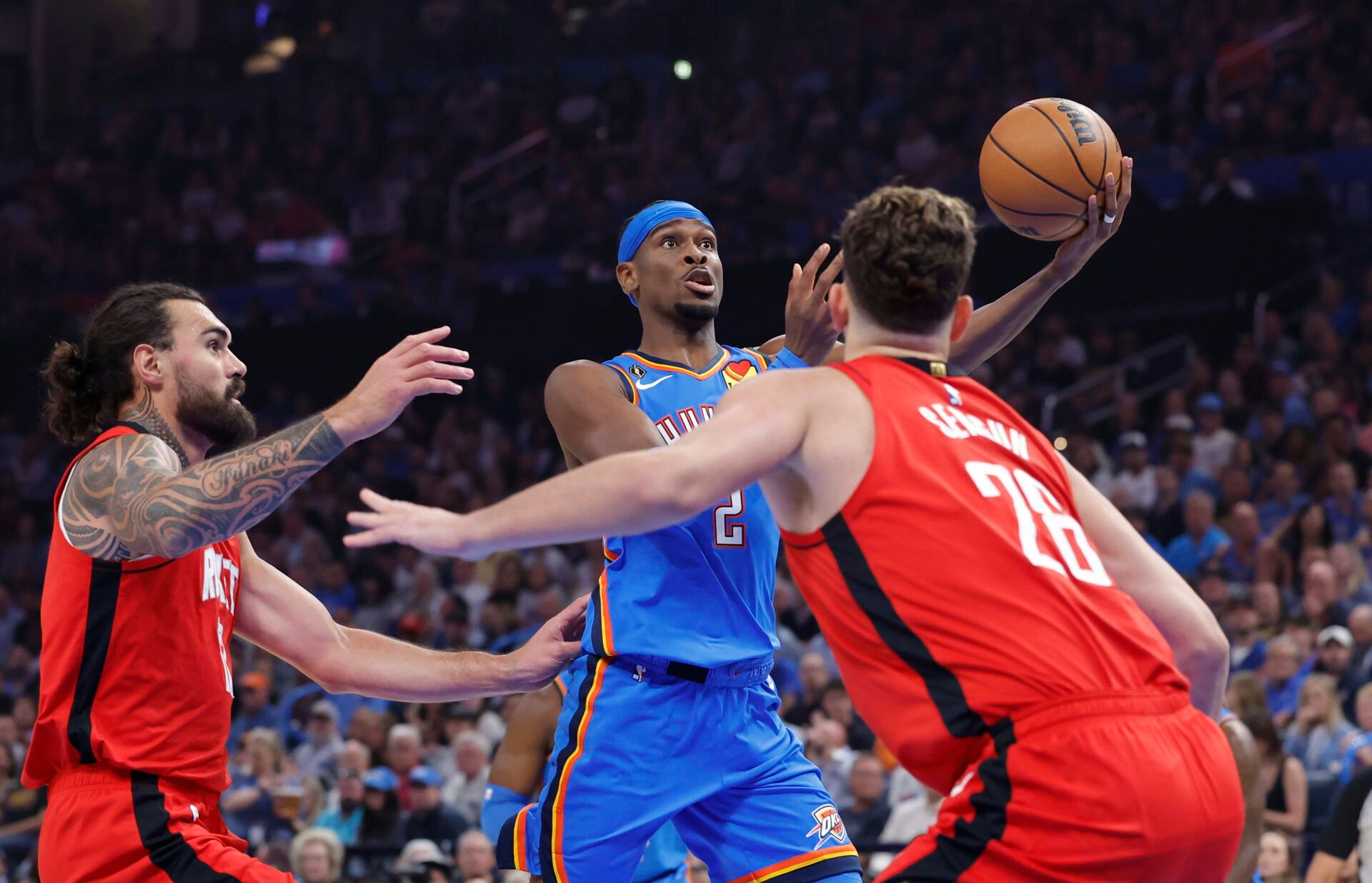Oklahoma City Thunder guard Shai Gilgeous-Alexander (2) shoots as Houston Rockets center Steven Adams (12) and center Alperen Sengun (28) defend during the first half at Paycom Center.