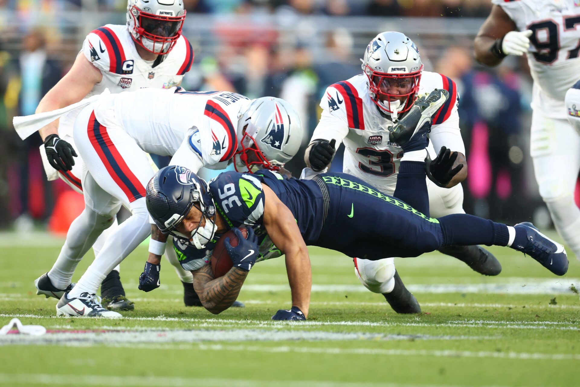 Seattle Seahawks running back George Holani (36) dives against New England Patriots cornerback Carlton Davis III (7) and linebacker Anfernee Jennings (33) during the second quarter in Super Bowl LX at Levi's Stadium.