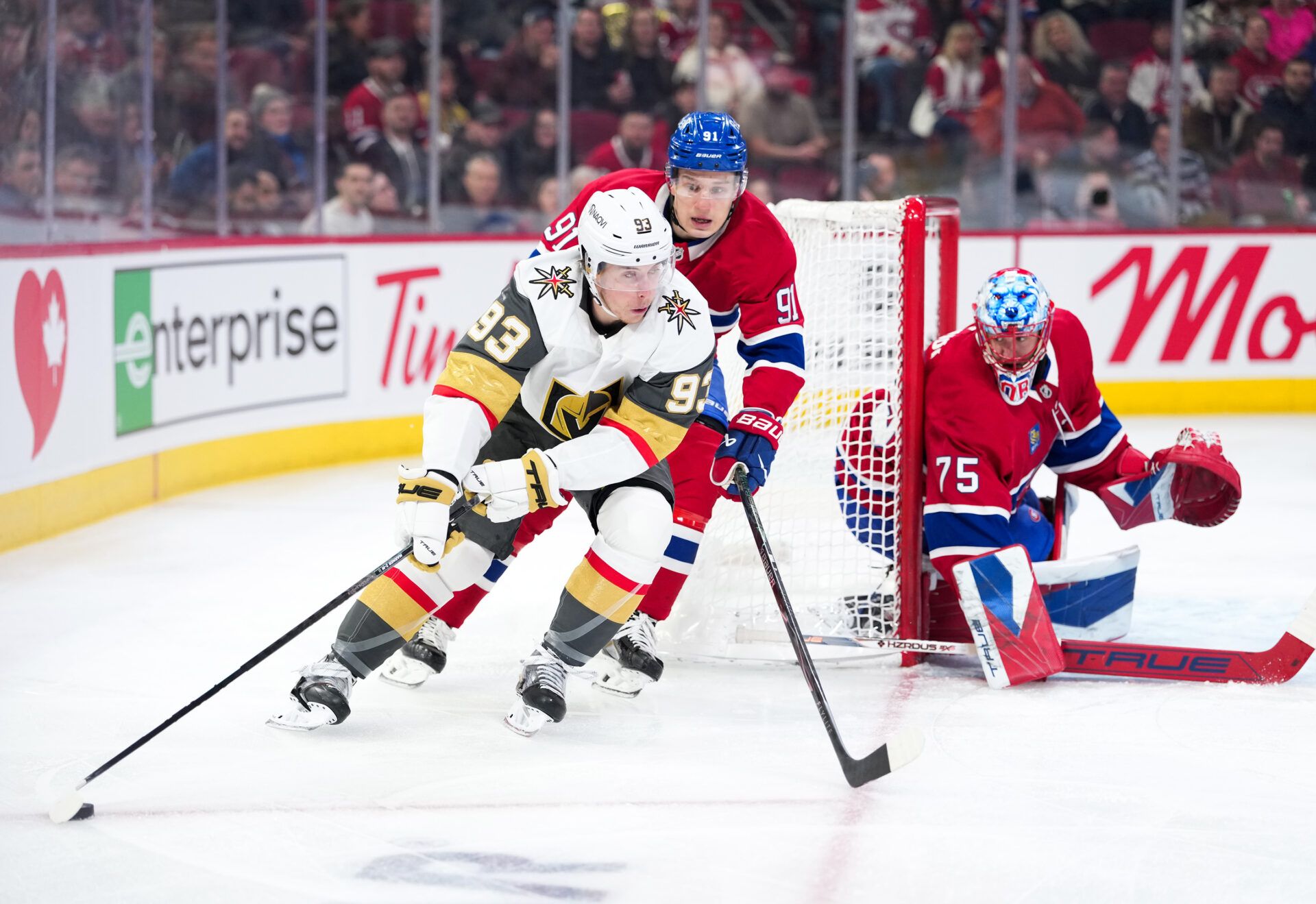Vegas Golden Knights forward Mitch Marner (93) plays the puck around the net of Montreal Canadiens goalie Jakub Dobes (75) as teammate forward Oliver Kapanen (91) defends during the first period at the Bell Centre.