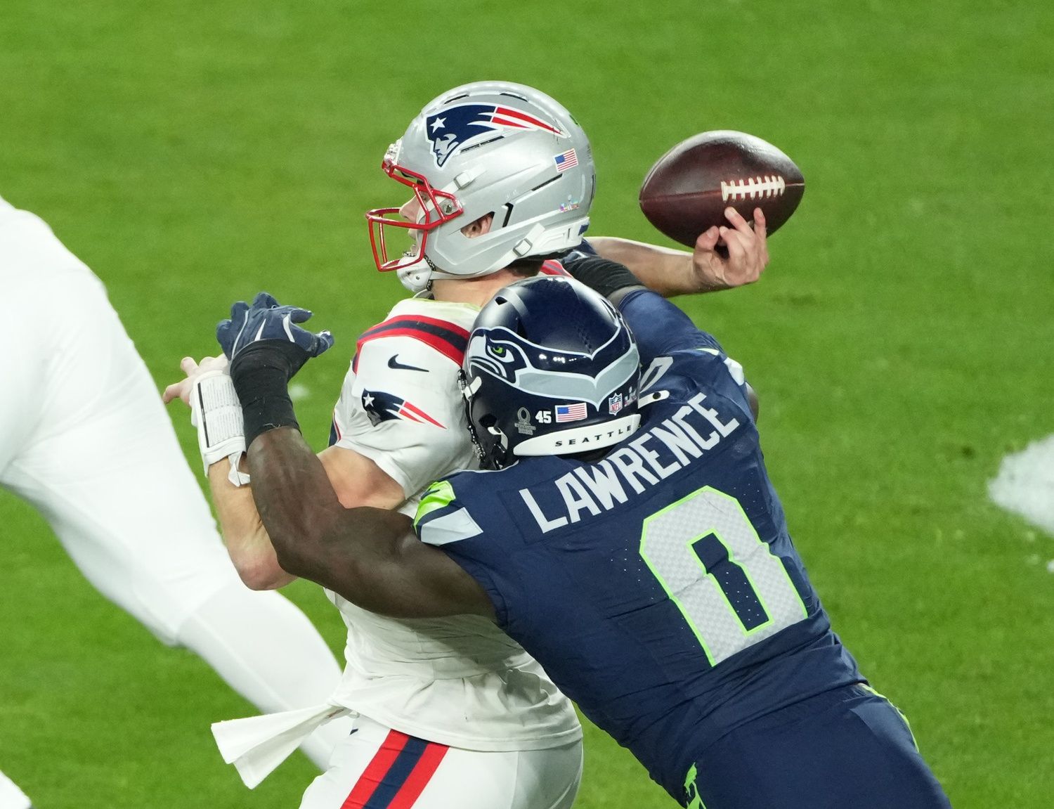 New England Patriots quarterback Drake Maye (10) is hit as he throws by Seattle Seahawks defensive end DeMarcus Lawrence (0) in the second half in Super Bowl LX at Levi's Stadium.