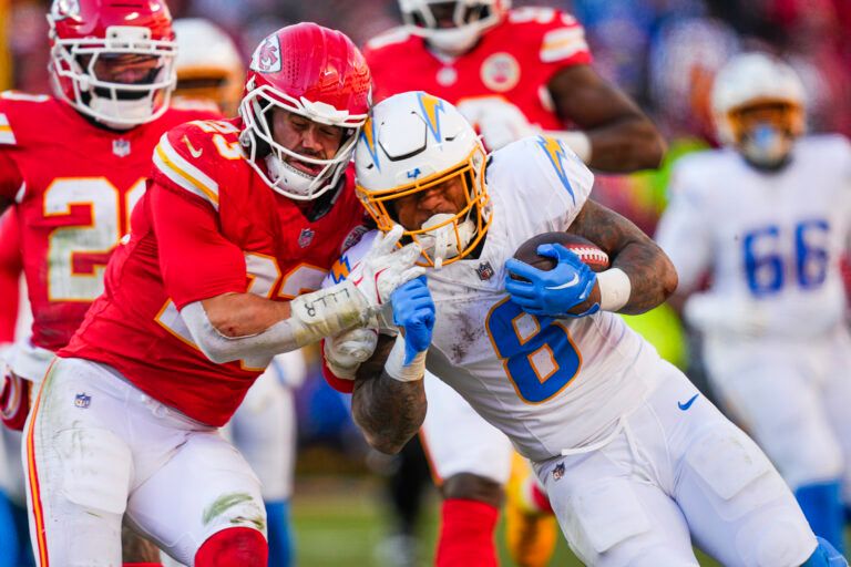 Los Angeles Chargers running back Omarion Hampton (8) rushes against Kansas City Chiefs linebacker Drue Tranquill (23) during the second half at GEHA Field at Arrowhead Stadium.