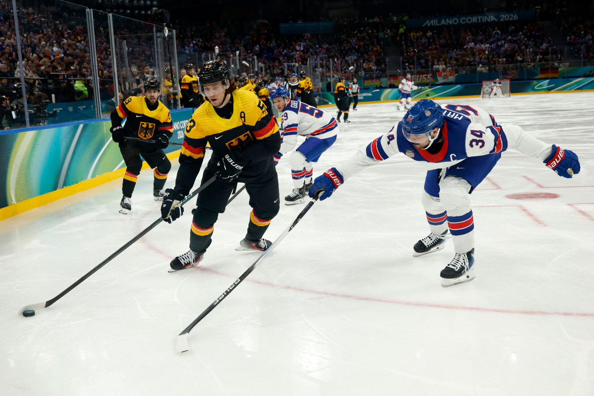 Moritz Seider of Germany in action with Auston Matthews of United States in men's ice hockey group C play during the Milano Cortina 2026 Olympic Winter Games at Milano Santagiulia Ice Hockey Arena.
