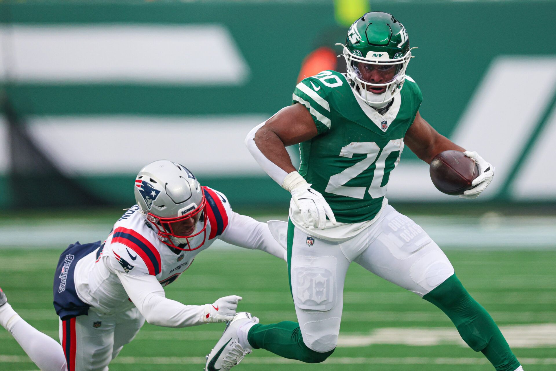 New York Jets running back Breece Hall (20) carries the ball as New England Patriots linebacker K'Lavon Chaisson (44) pursues at MetLife Stadium.