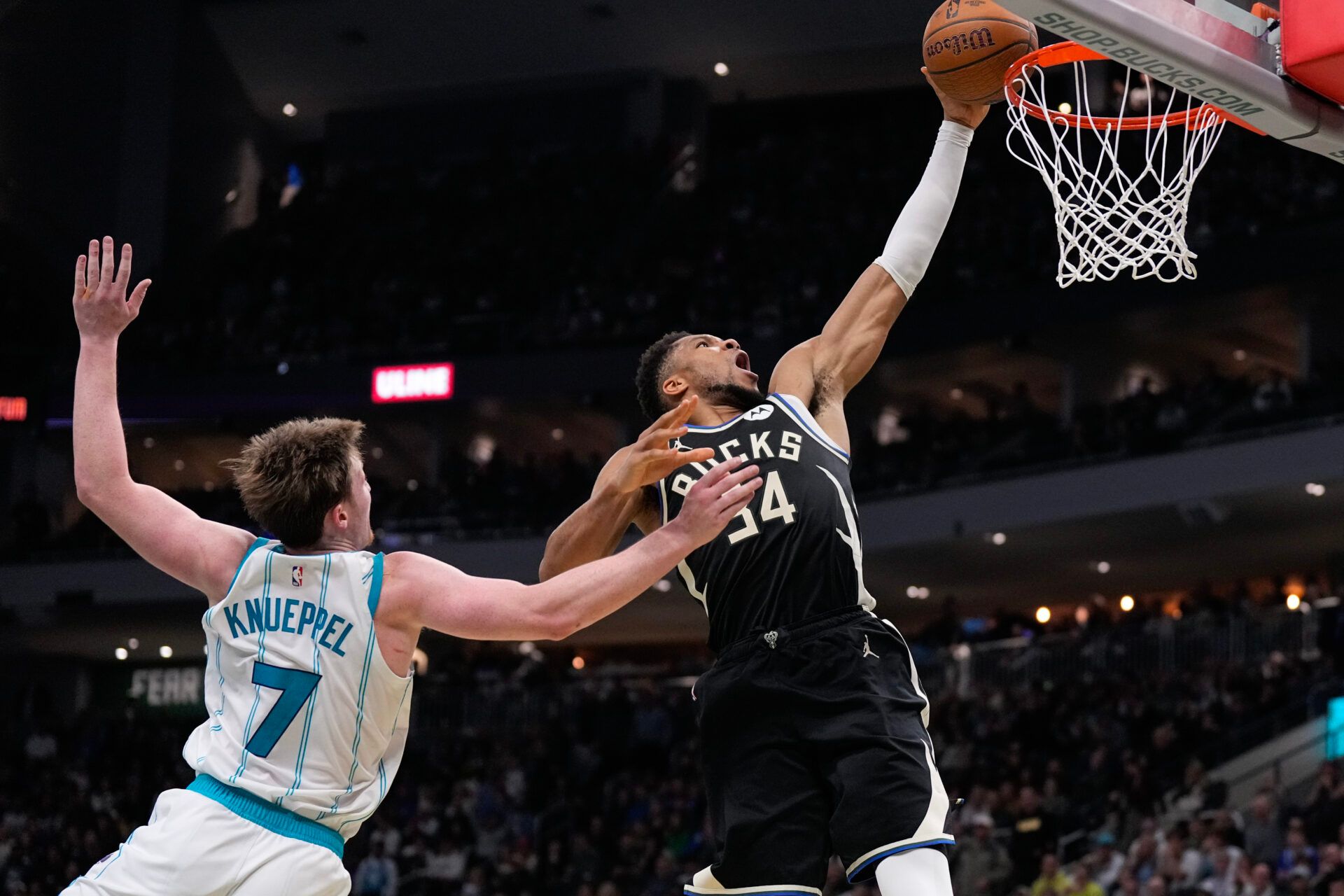 Milwaukee Bucks forward Giannis Antetokounmpo (34) dunks as Charlotte Hornets guard Kon Knueppel (7) defends during overtime at Fiserv Forum.