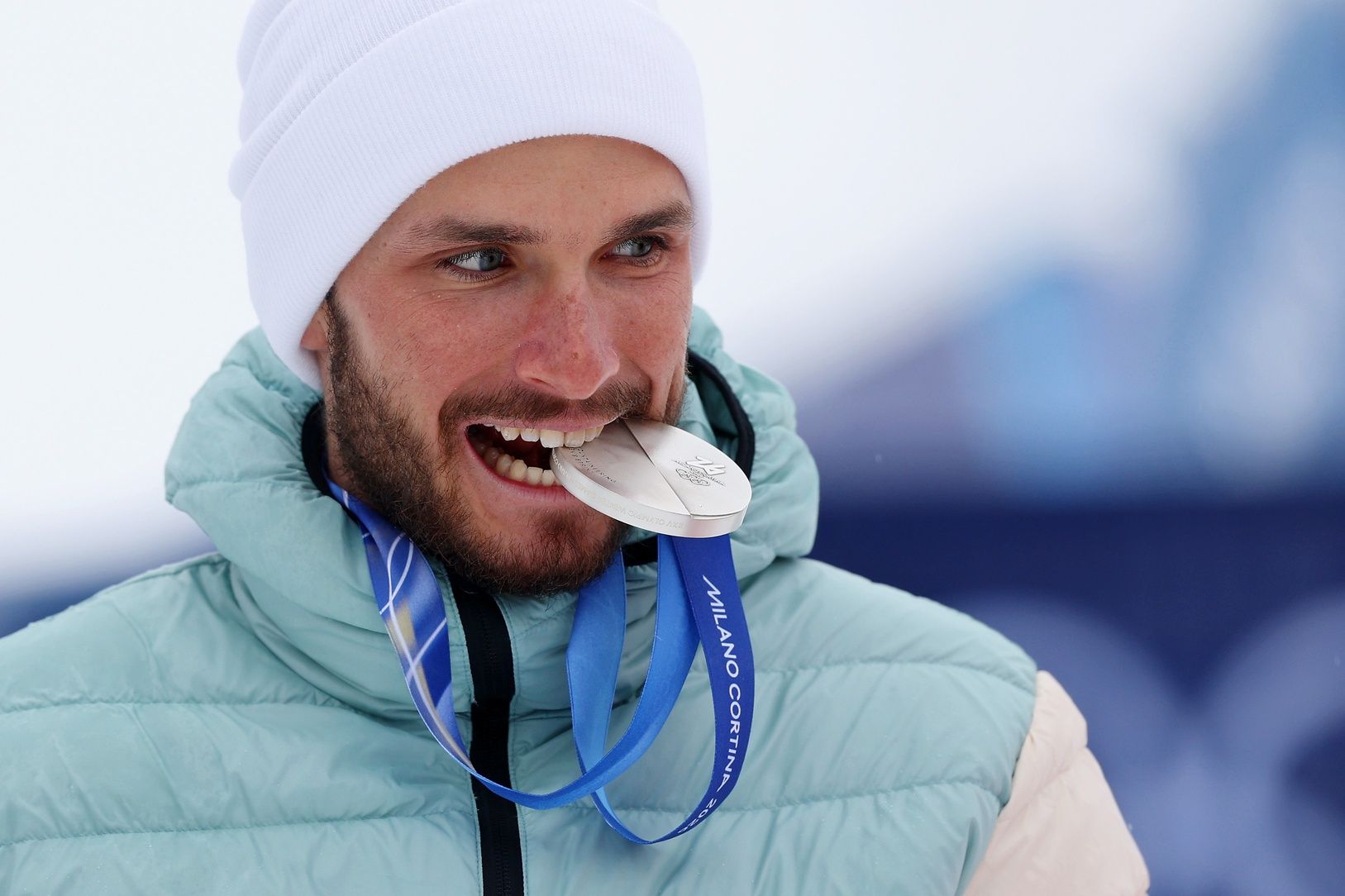 Silver medalist Nikita Filippov of Individual Neutral Athletes bites his medal during the medal ceremony for men's ski mountaineering during the Milano Cortina 2026 Olympic Winter Games at Stelvio Ski Centre.