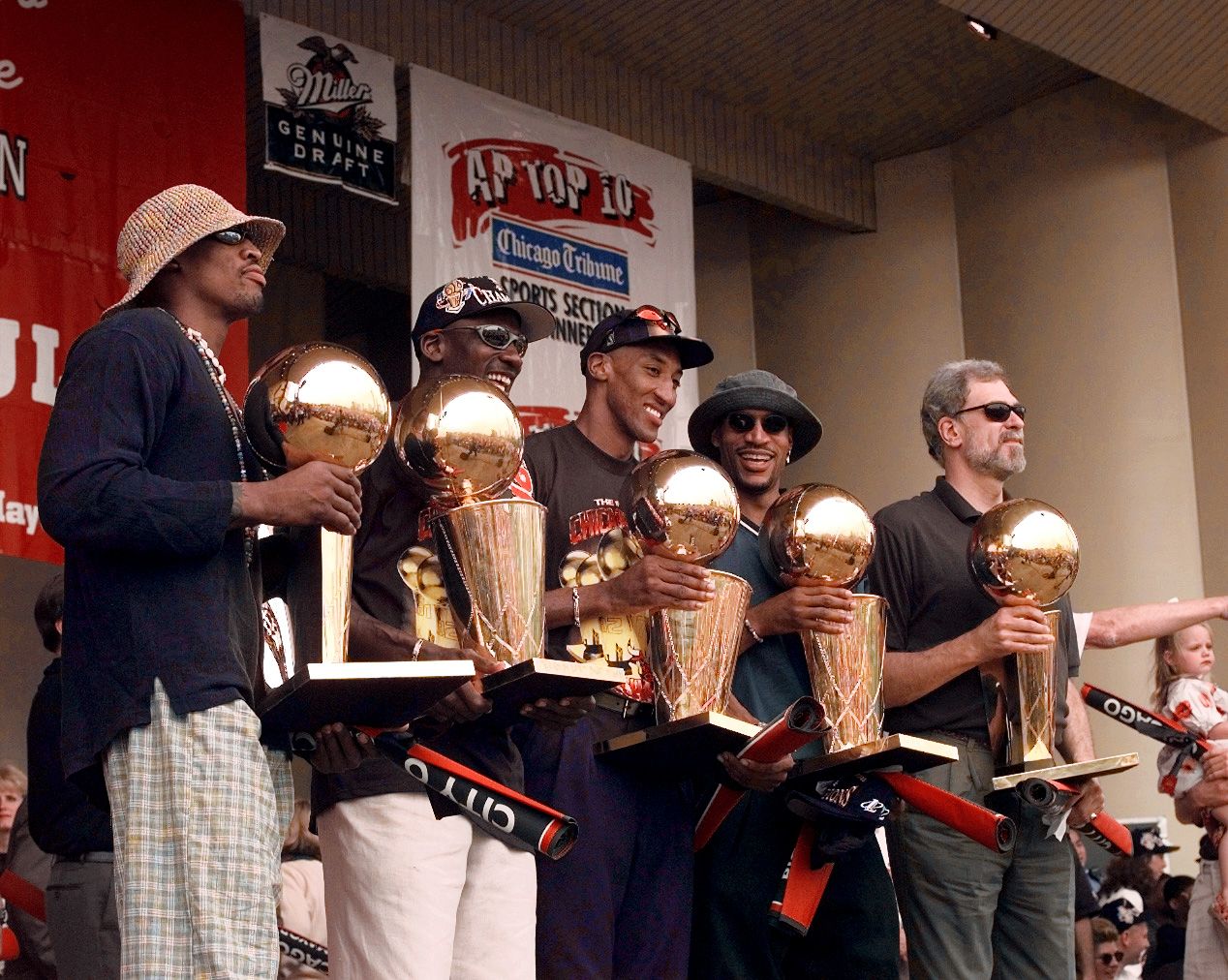 Chicago Bulls players, left to right,  Ron Harper, Dennis Rodman, Scottie Pippen, Michael Jordan & coach Phil Jackson hold up the Bulls' five championship trophies at a rally in Grant Park.
