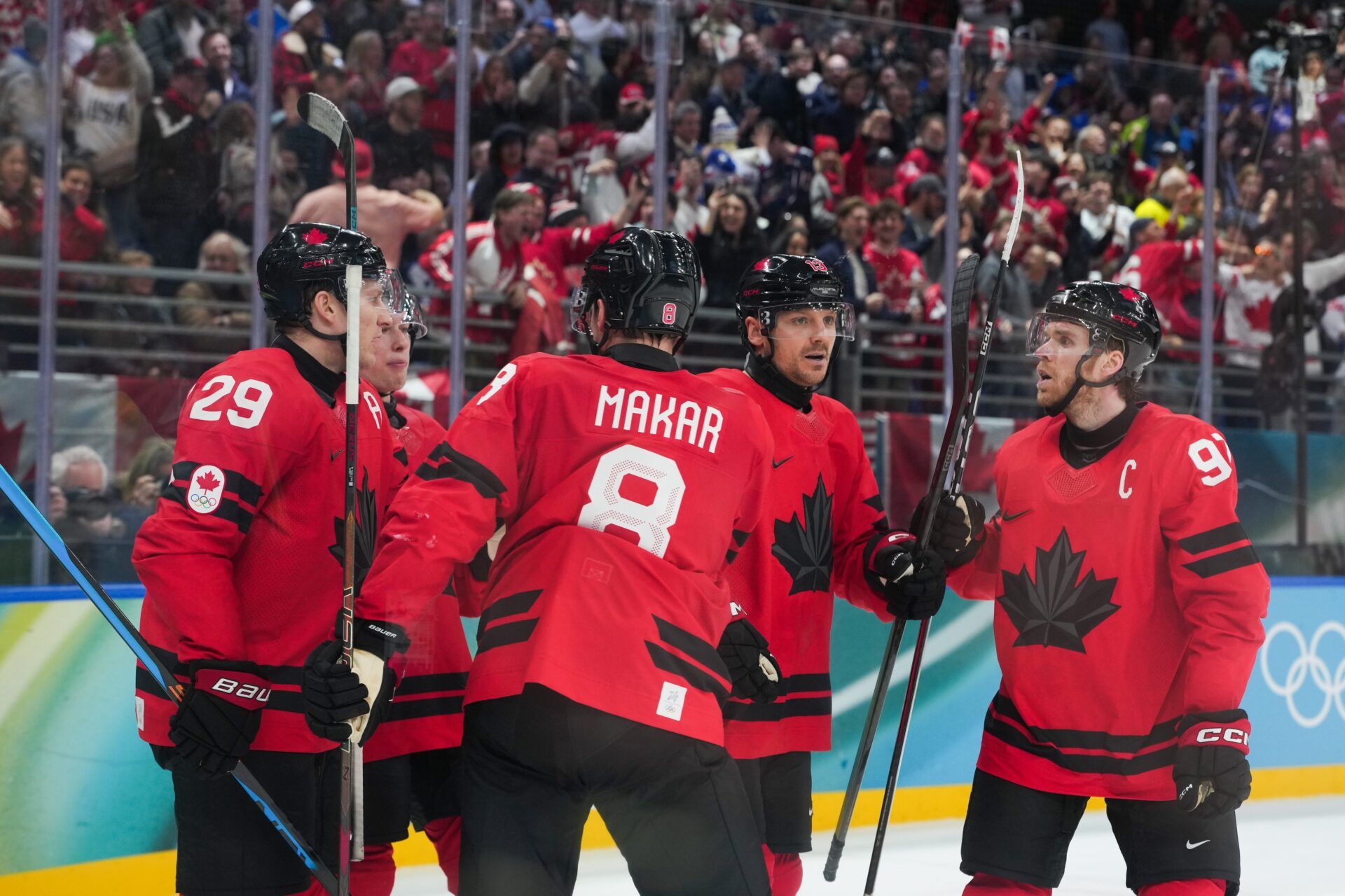 Cale Makar (8) of Canada celebrates with Nathan MacKinnon (29) of Canada and Sam Reinhart (13) of Canada after assisting a goal during the second period against Finland in a men's ice hockey semifinal during the Milano Cortina 2026 Olympic Winter Games at Milano Santagiulia Ice Hockey Arena.