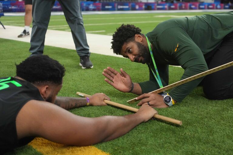 Green Bay Packers assistant strength and assistant coach Todd Hunt measures flexibility of LSU offensive lineman Miles Frazier (OL15) during the 2025 NFL Scouting Combine at Lucas Oil Stadium.