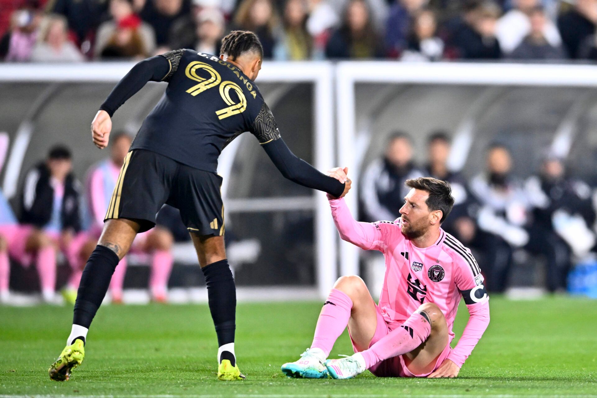 Los Angeles FC forward Denis Bouanga (99) helps Inter Miami CF forward Lionel Messi (10) up off the ground during the second half at Los Angeles Memorial Coliseum.