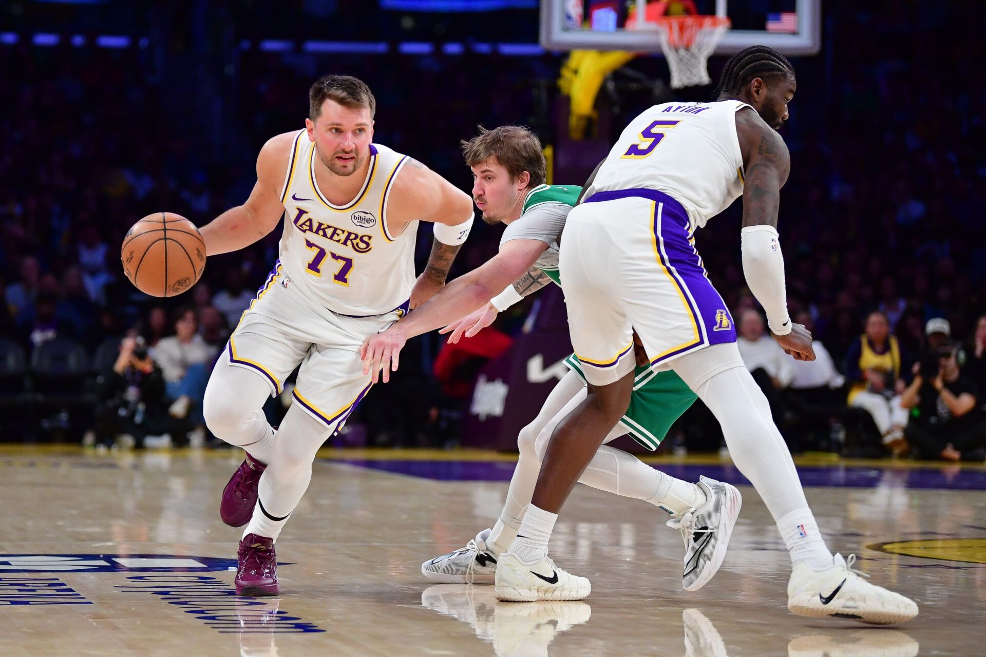 Los Angeles Lakers guard Luka Doncic (77) moves the ball as center Deandre Ayton (5) provides coverage against Boston Celtics guard Baylor Scheierman (55) during the second half at Crypto.com Arena.