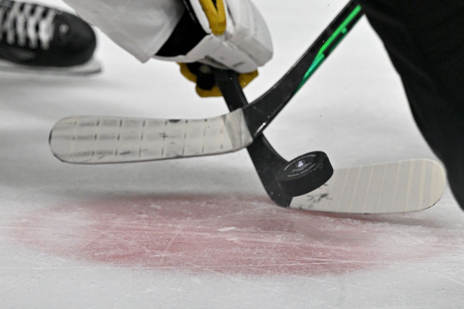 A view of an NHL puck with the Stanley Cup logo and hockey sticks and the face-off circle during the third period of the game between the Dallas Stars and the Vegas Golden Knights in game six of the Western Conference Finals of the 2023 Stanley Cup Playoffs at American Airlines Center.