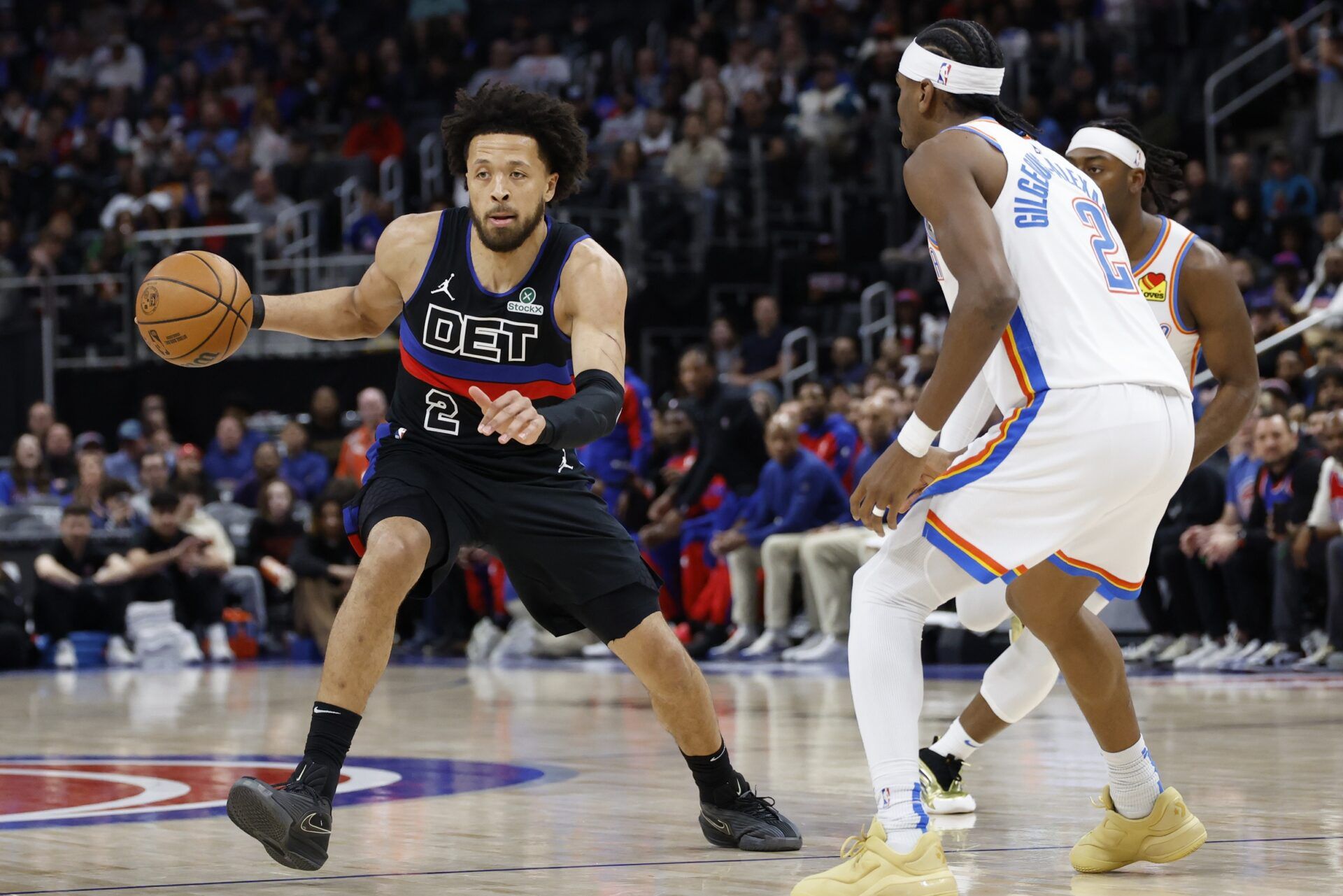 Detroit Pistons guard Cade Cunningham (2) dribbles defended by Oklahoma City Thunder guard Shai Gilgeous-Alexander (2) in the first half at Little Caesars Arena.