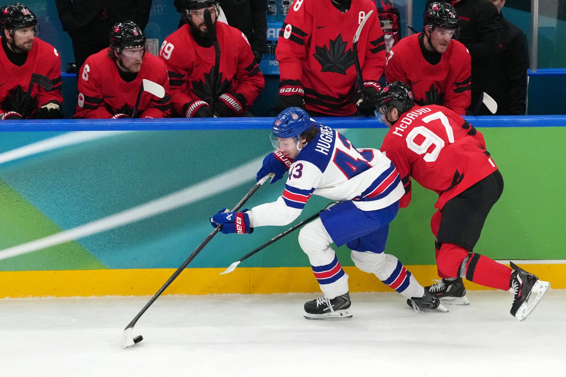 Quinn Hughes of the United States battles for the puck against Connor McDavid of Canada during the men's ice hockey gold medal game during the Milano Cortina 2026 Olympic Winter Games at Milano Santagiulia Ice Hockey Arena.