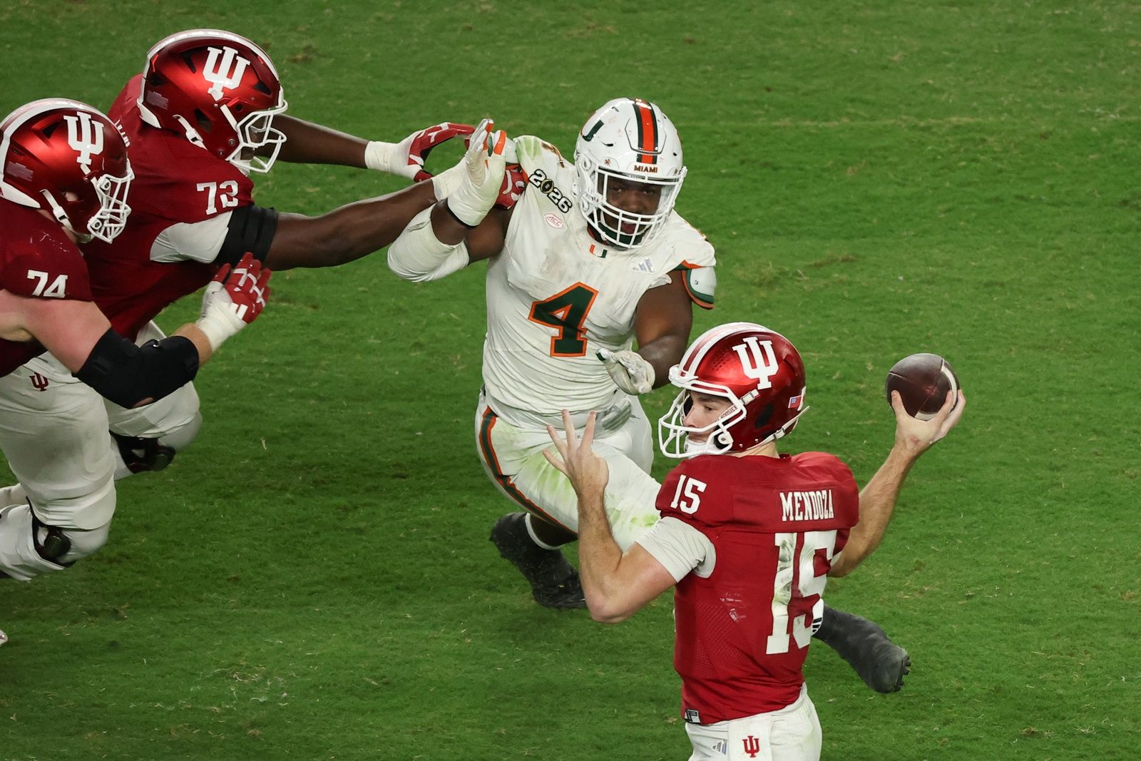 Indiana Hoosiers quarterback Fernando Mendoza (15) passes the ball under pressure by Miami Hurricanes defensive lineman Rueben Bain Jr. (4) in the third quarter during the College Football Playoff National Championship game at Hard Rock Stadium.