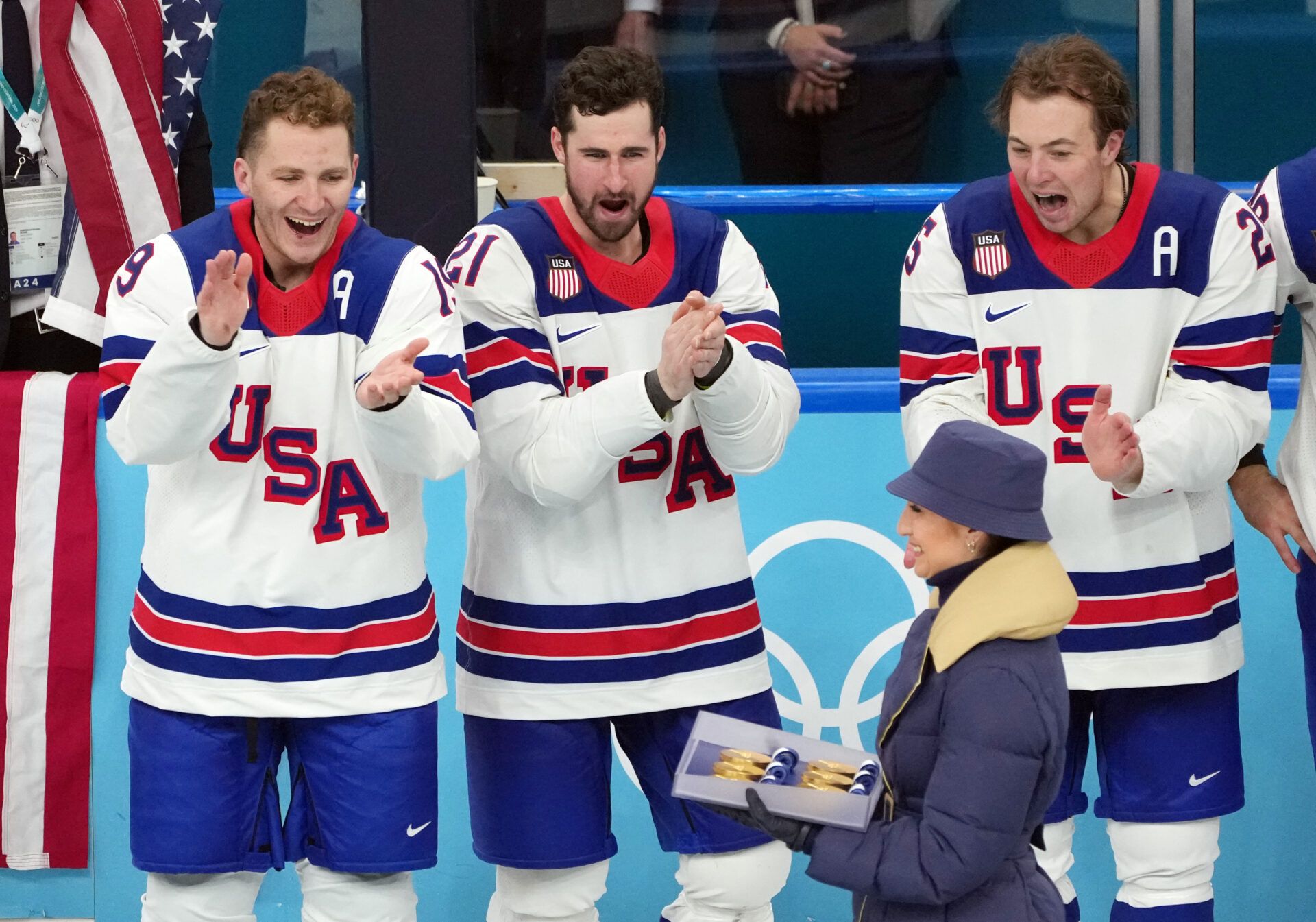 Matthew Tkachuk (19), Dylan Larkin (21) and Charlie McAvoy (25) look at the medals after defeating Canada in the men's ice hockey gold medal game during the Milano Cortina 2026 Olympic Winter Games at Milano Santagiulia Ice Hockey Arena.