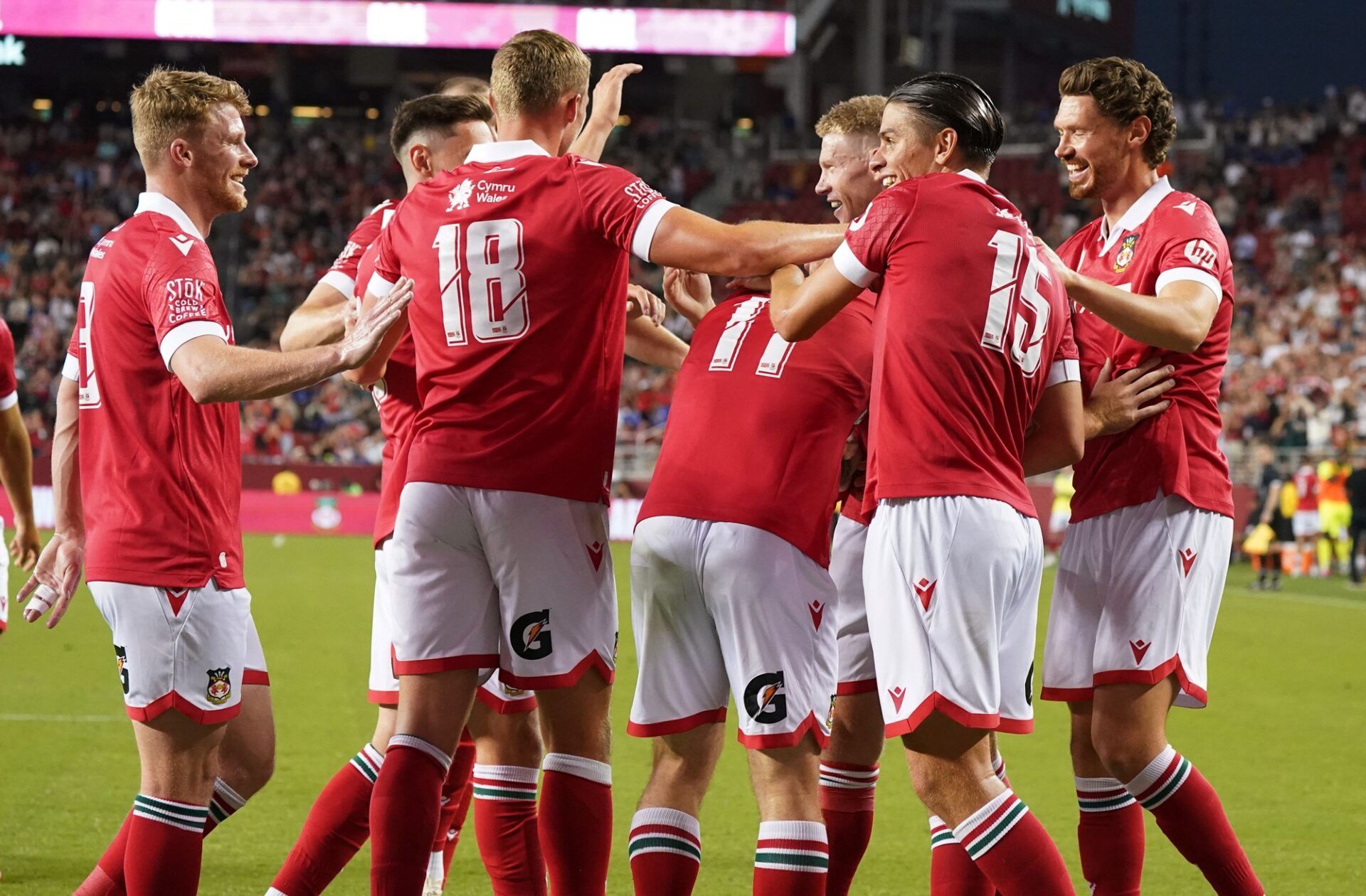 Wrexham midfielder Andy Cannon (8), Wrexham forward Sam Dalby (18), Wrexham midfielder James McClean (23), Wrexham midfielder George Dobson (15), and Wrexham midfielder George Evans (12) celebrate with Wrexham forward Jack Marriott (11) after he scores a goal against Chelsea in the second half at Levi's Stadium.