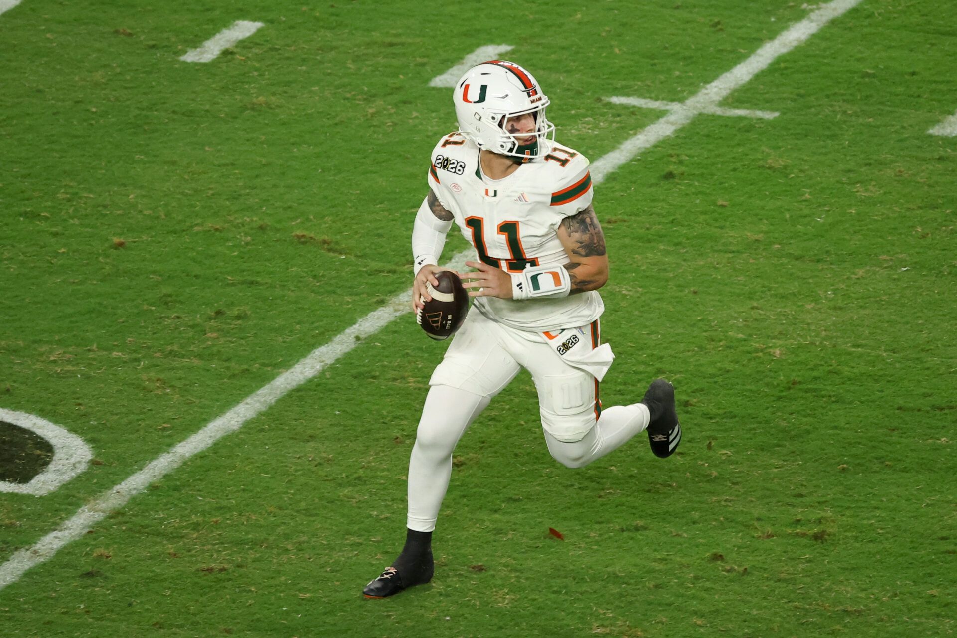 Miami Hurricanes quarterback Carson Beck (11) scrambles with the ball against the Indiana Hoosiers in the third quarter during the College Football Playoff National Championship game at Hard Rock Stadium.