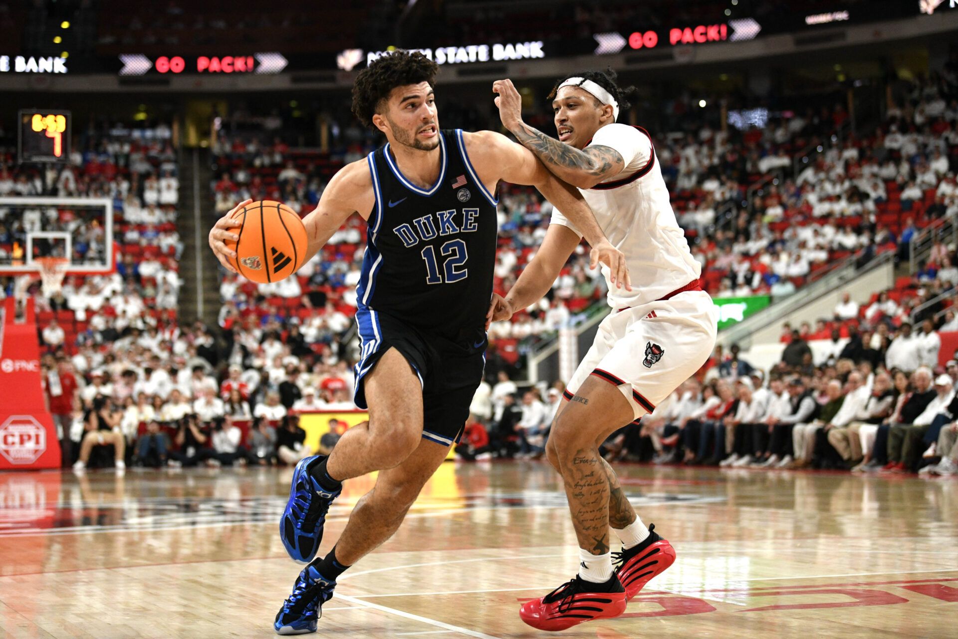 Duke Blue Devils forward Cameron Boozer (12) drives the ball around NC State Wolfpack forward Darrion Williams (1) during the first half at Lenovo Center.