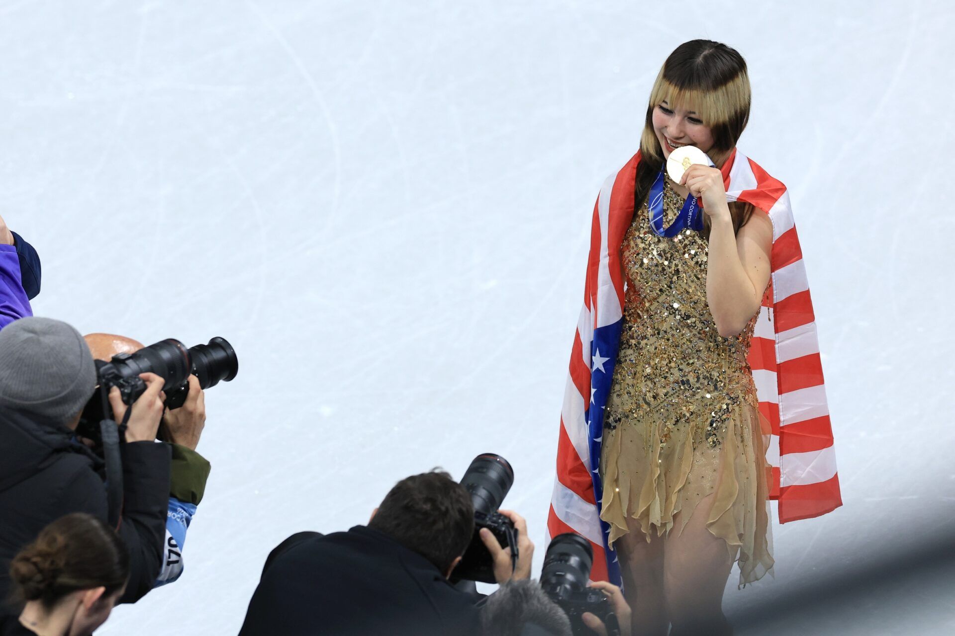 Alysa Liu of the United States celebrates with the gold medal and the flag after the medal ceremony for the women's free skate during the Milano Cortina 2026 Olympic Winter Games at Milano Ice Skating Arena.
