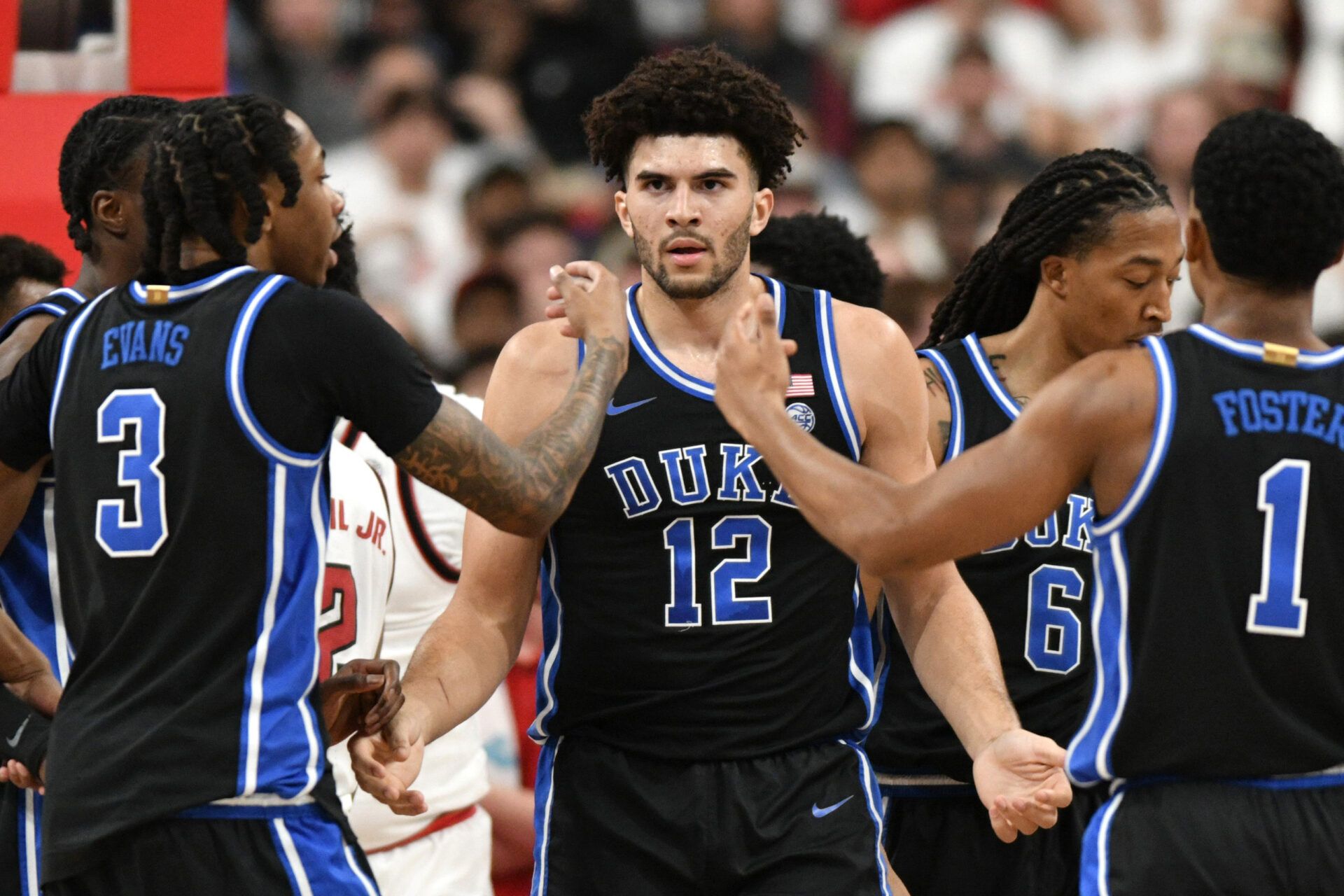 Duke Blue Devils forward Cameron Boozer (12) reacts with guard Isaiah Evans (3) and guard Caleb Foster (1) after being fouled during the first half against the NC State Wolfpack at Lenovo Center.