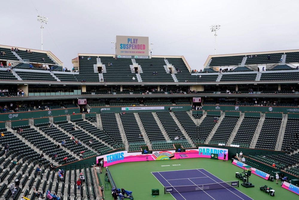 Some tennis fans linger in a mostly empty Stadium 1 as morning rain suspends play between Iga Swiatek and Karolina Muchova at the BNP Paribas Open in Indian Wells, Calif., on Tuesday, March 11, 2025.