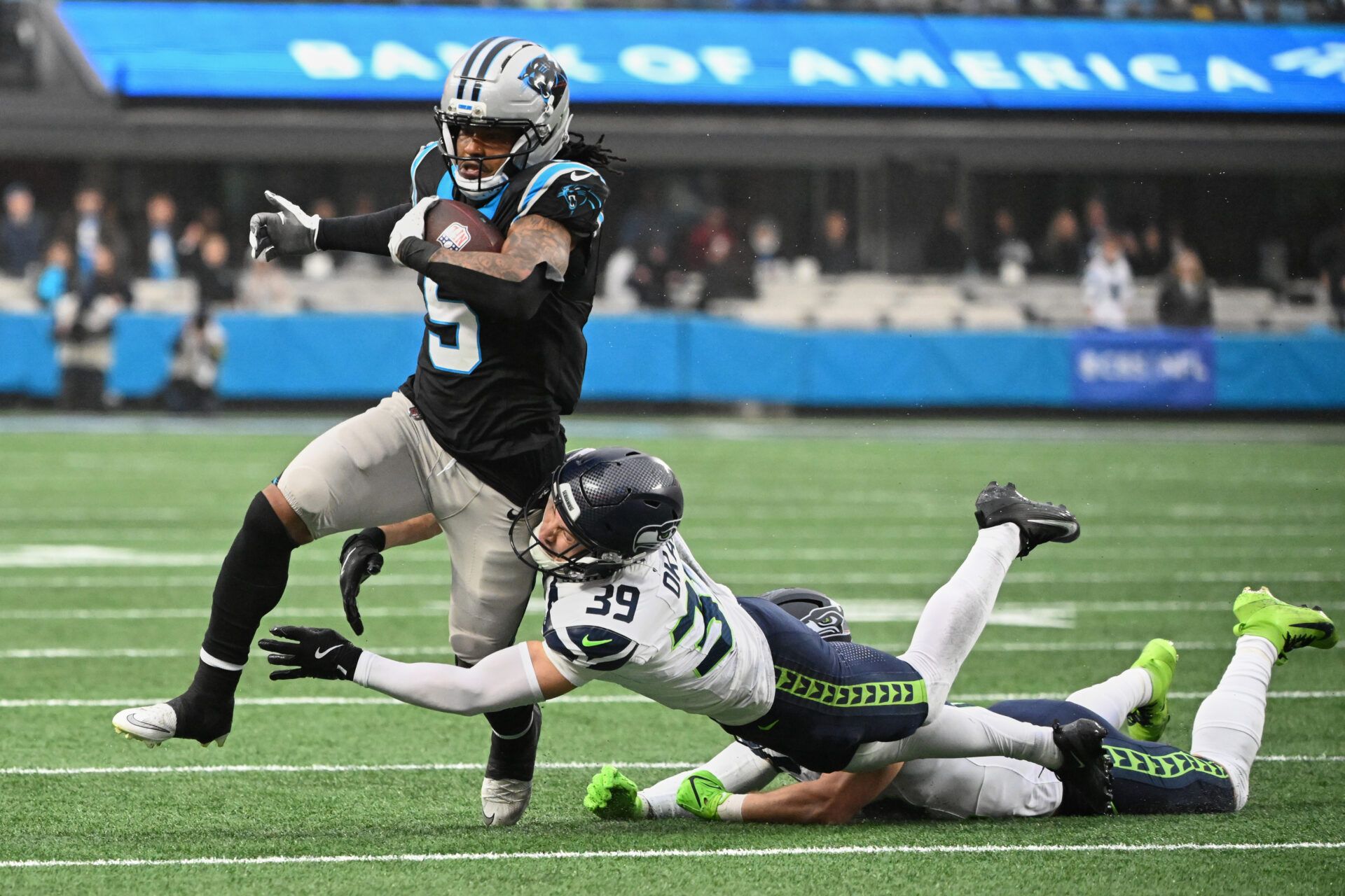 Carolina Panthers running back Rico Dowdle (5) runs the ball against Seattle Seahawks safety Ty Okada (39) and linebacker Drake Thomas (42) (obscured) during the second quarter at Bank of America Stadium.