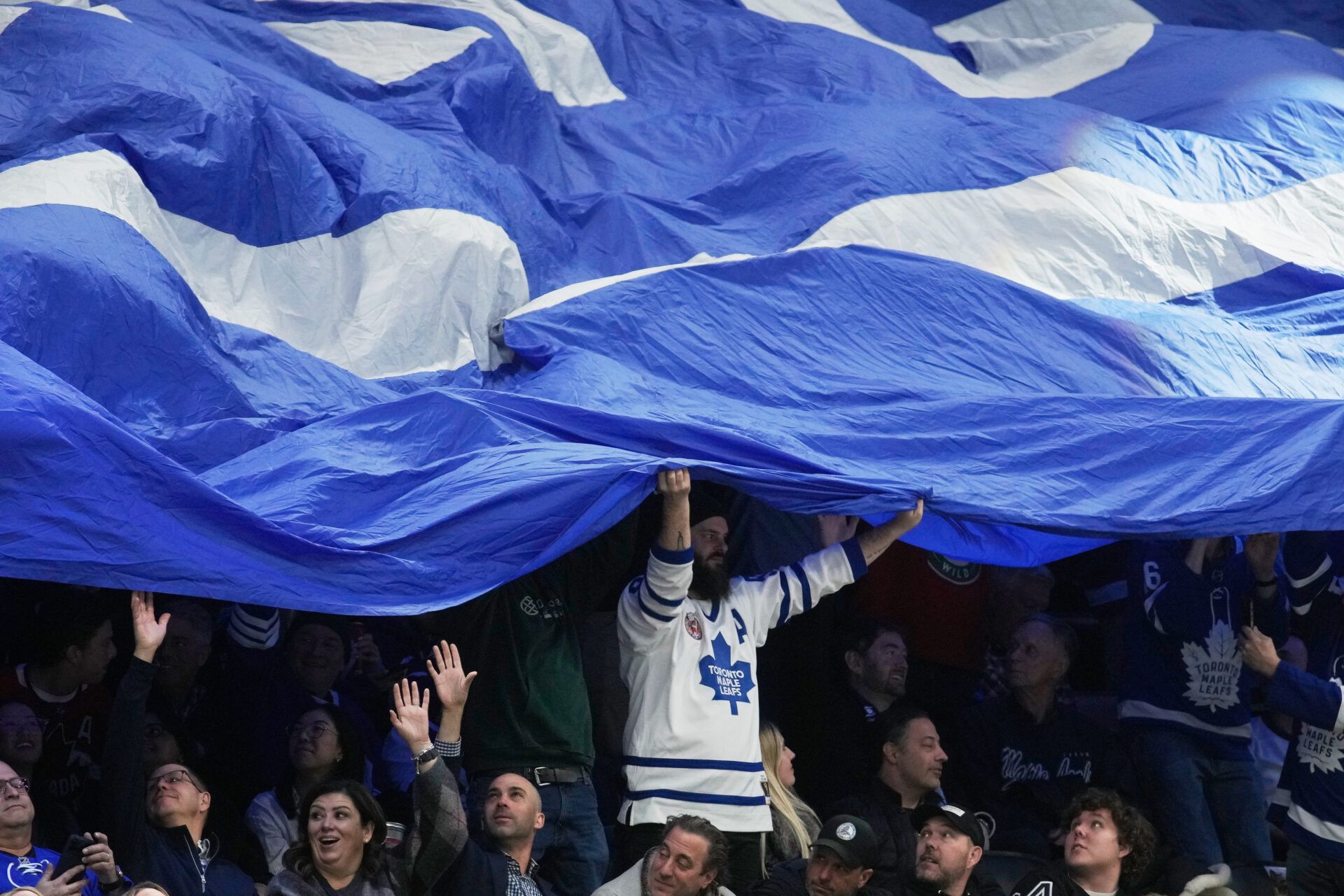 A Toronto Maple Leafs fan holds a large flag in the stands at Scotiabank Arena.