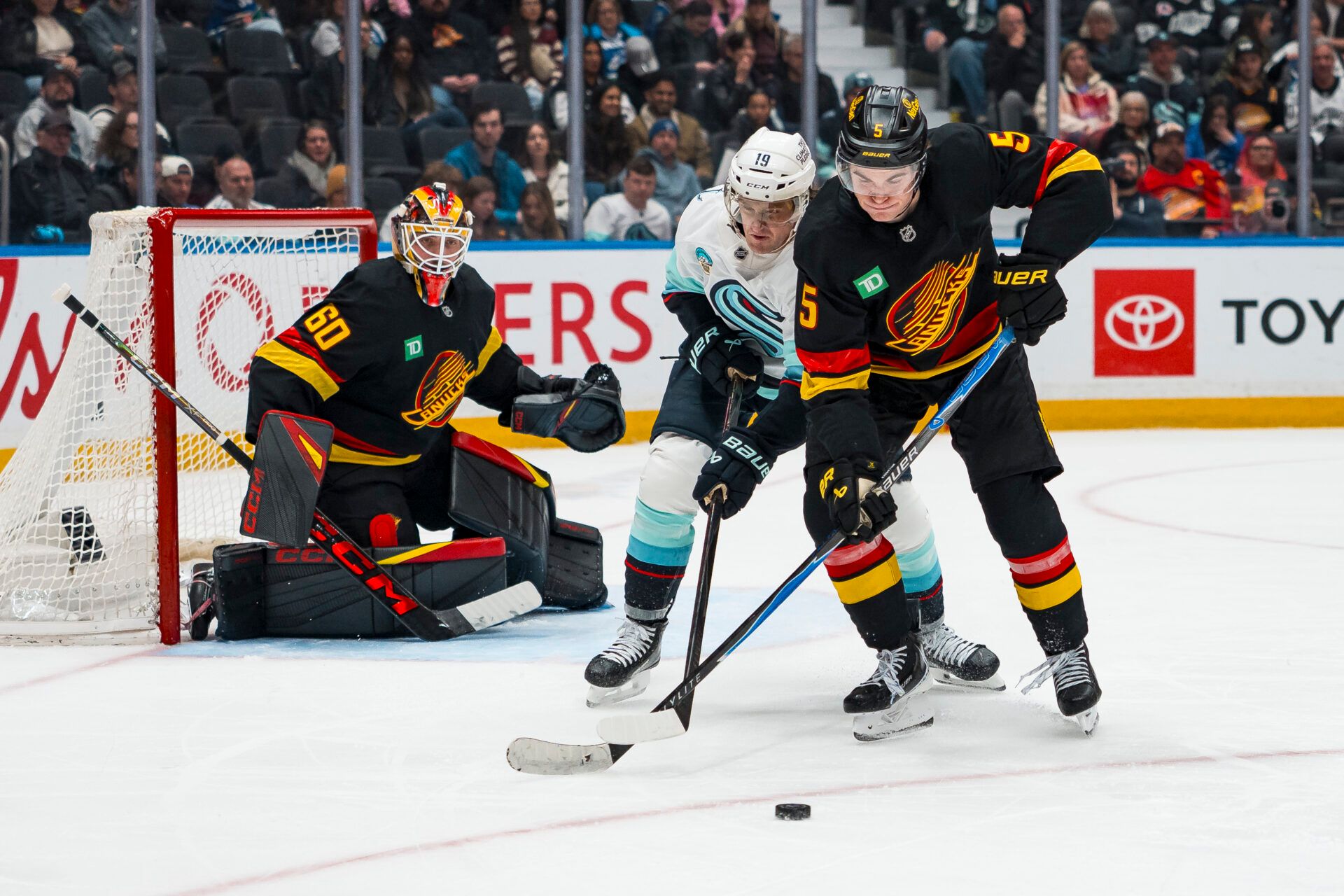 Vancouver Canucks goalie Nikita Tolopilo (60) watches as Seattle Kraken forward Jared McCann (19) stick checks defenseman Tom Willander (5) in the third period at Rogers Arena.