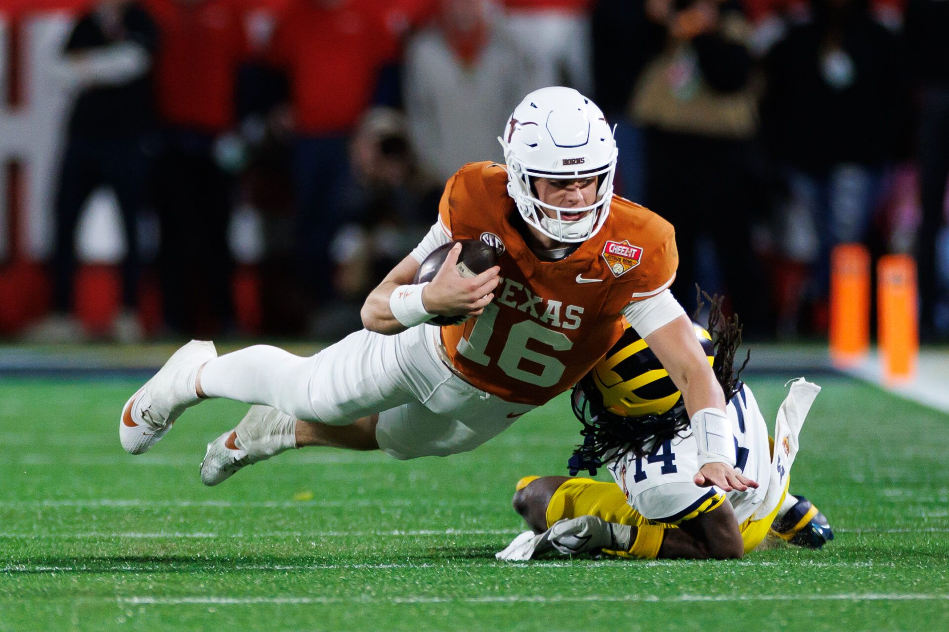 Texas Longhorns quarterback Arch Manning (16) dives forward over Michigan Wolverines defensive back Jordan Young (14) during the second half at Camping World Stadium.