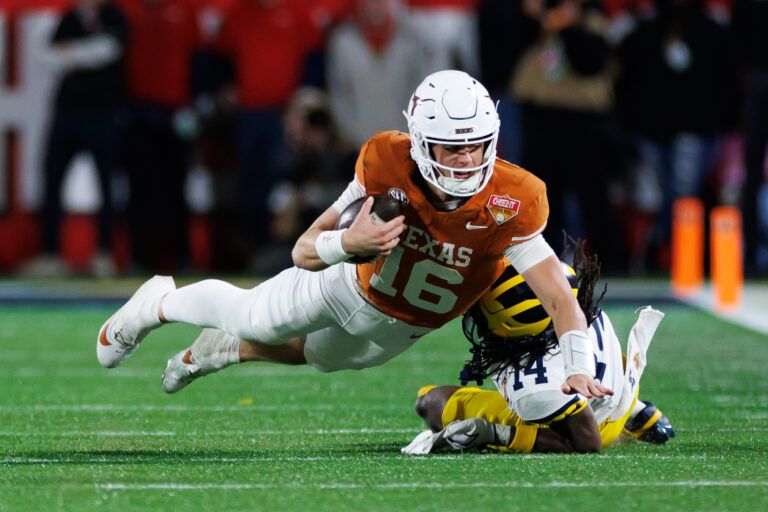 Texas Longhorns quarterback Arch Manning (16) dives forward over Michigan Wolverines defensive back Jordan Young (14) during the second half at Camping World Stadium.