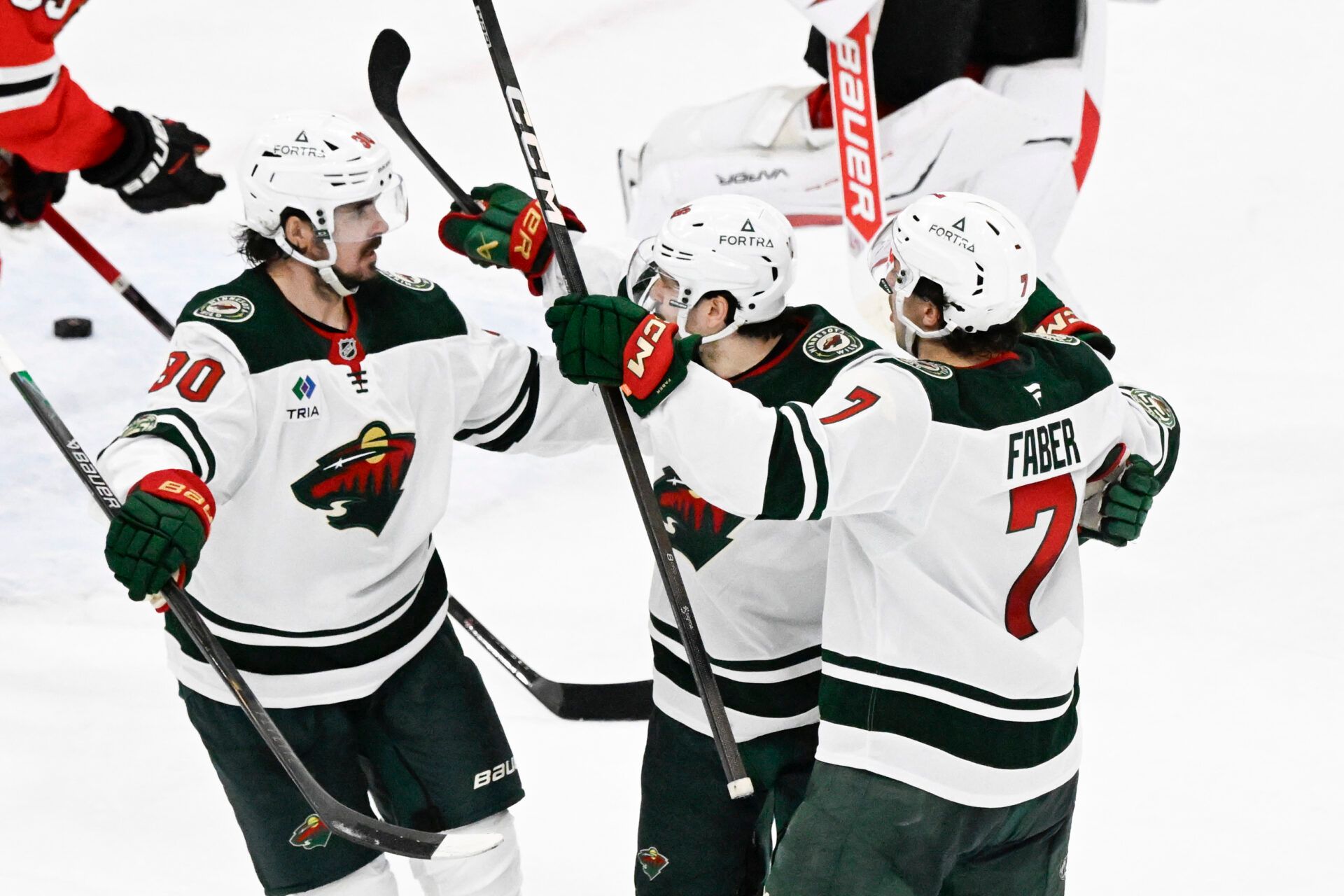Minnesota Wild right wing Mats Zuccarello (36) celebrates with  left wing Marcus Johansson (90) and  defenseman Brock Faber (7) after scoring a game winning goal during the overtime period against the Chicago Blackhawks at United Center.