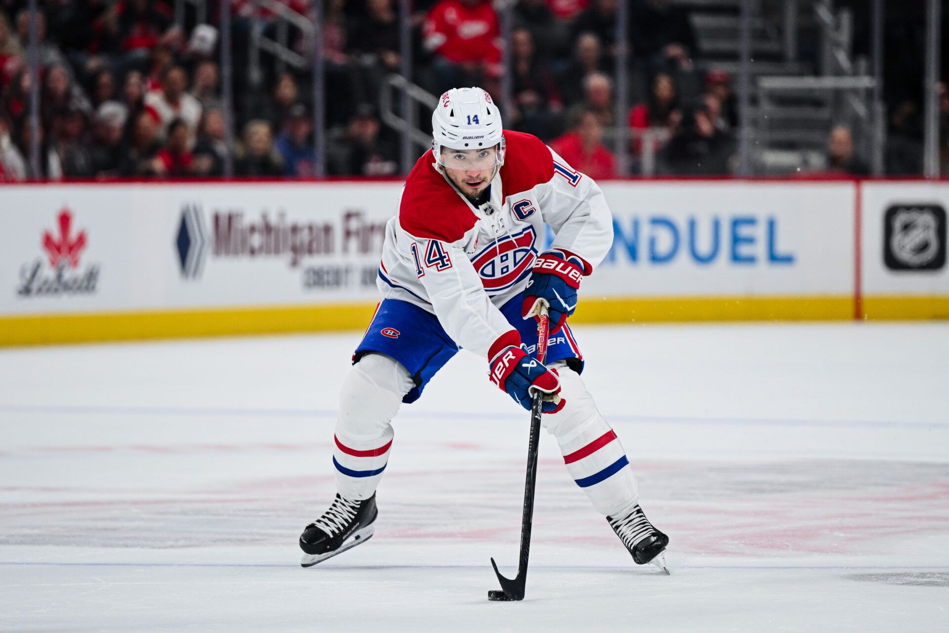 Montreal Canadiens center Nick Suzuki (14) brings the puck up ice during the first period against the Detroit Red Wings at Little Caesars Arena.