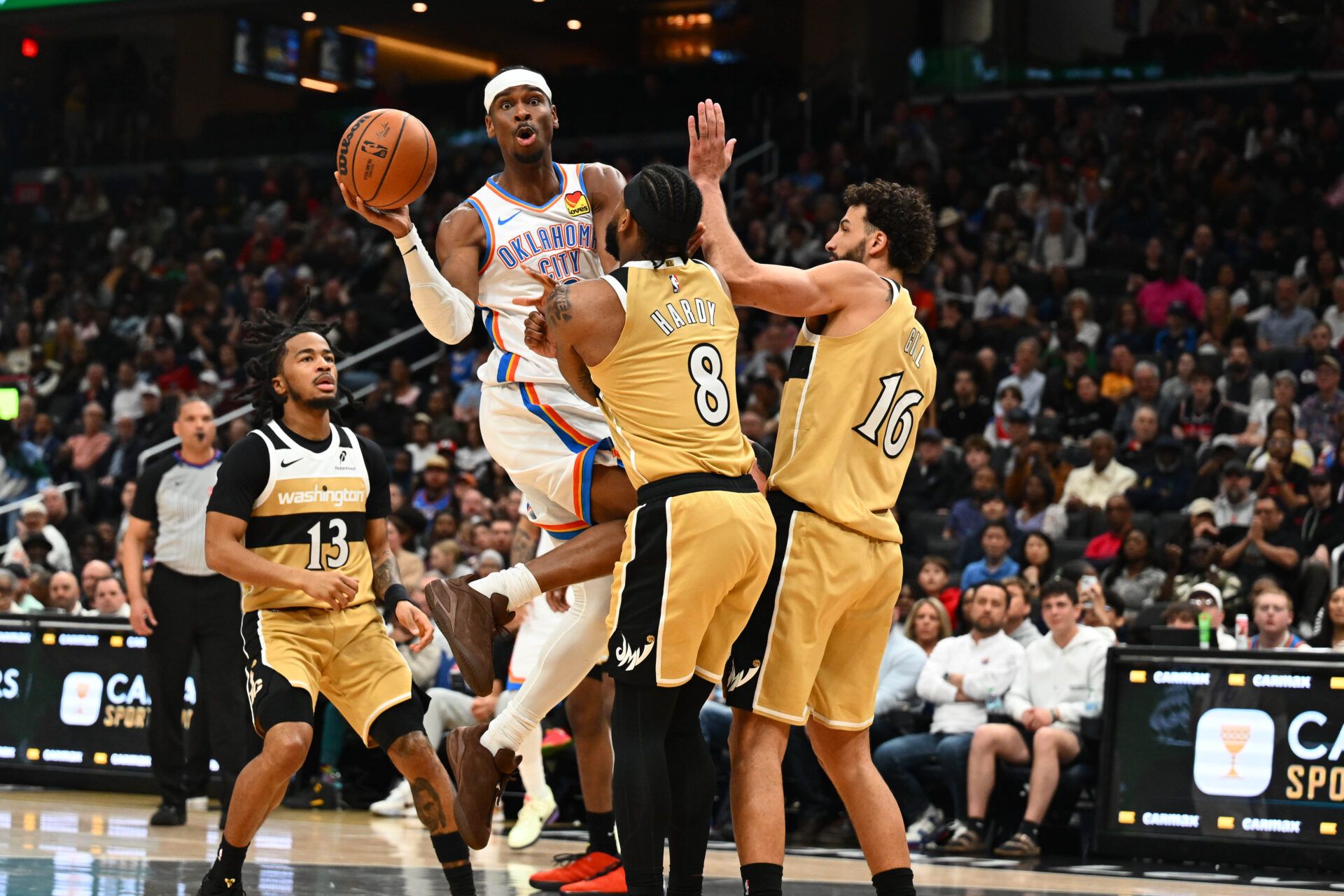 Oklahoma City Thunder guard Shai Gilgeous-Alexander (2) passes the ball past Washington Wizards guard Jaden Hardy (8) and forward Anthony Gill (16) during the second half at Capital One Arena.