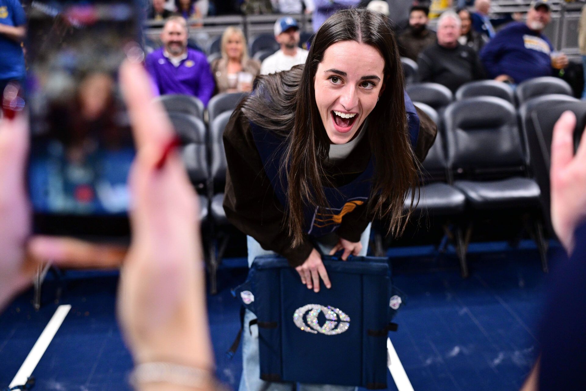 Indiana Fever guard Caitlin Clark reacts to her logo being on the back of her court chair before the game between the Indiana Pacers and the Los Angeles Lakers at Gainbridge Fieldhouse.