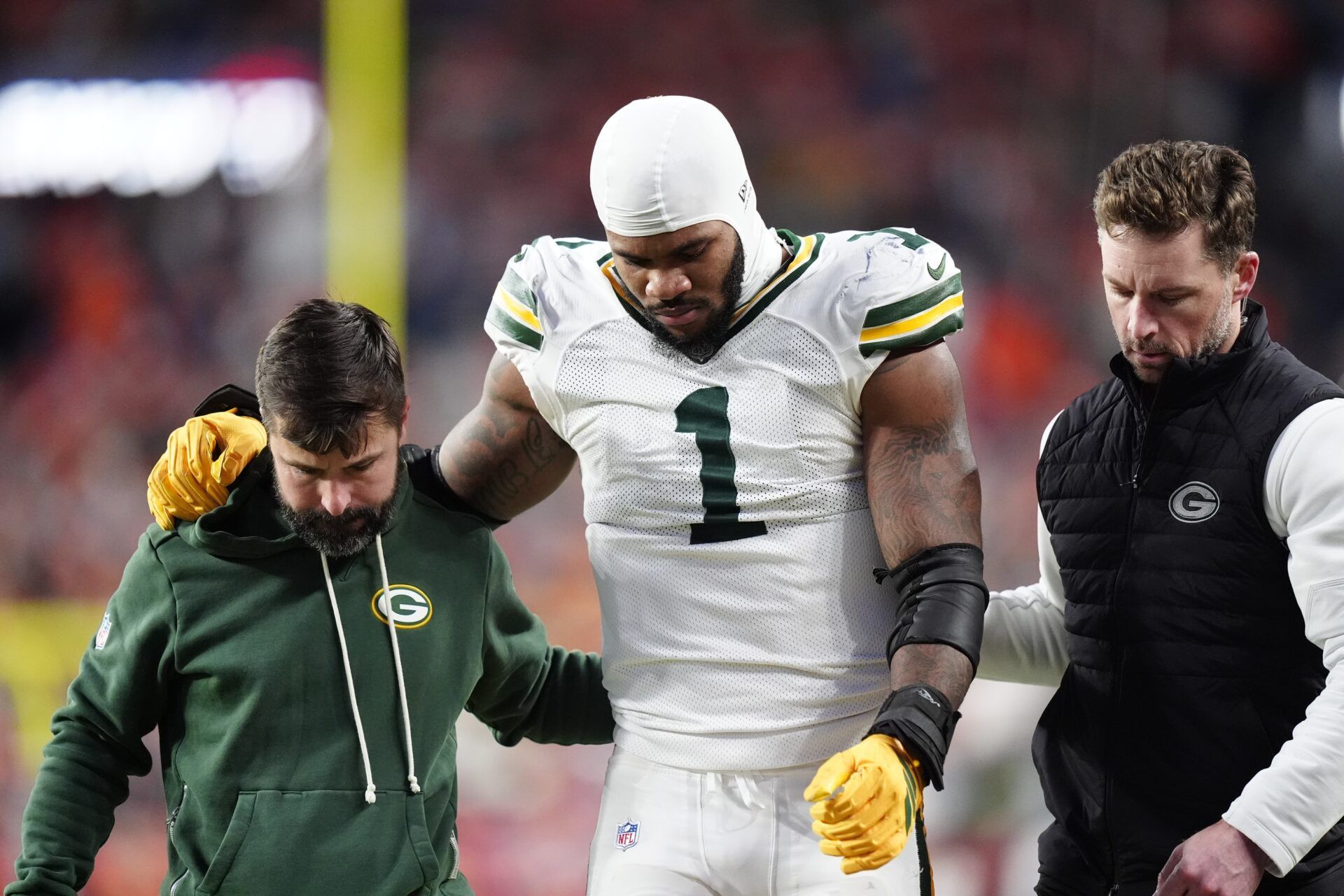 Green Bay Packers defensive end Micah Parsons (1) walks off the field with help from medical personnel following an injury during the third quarter against the Denver Broncos at Empower Field at Mile High.
