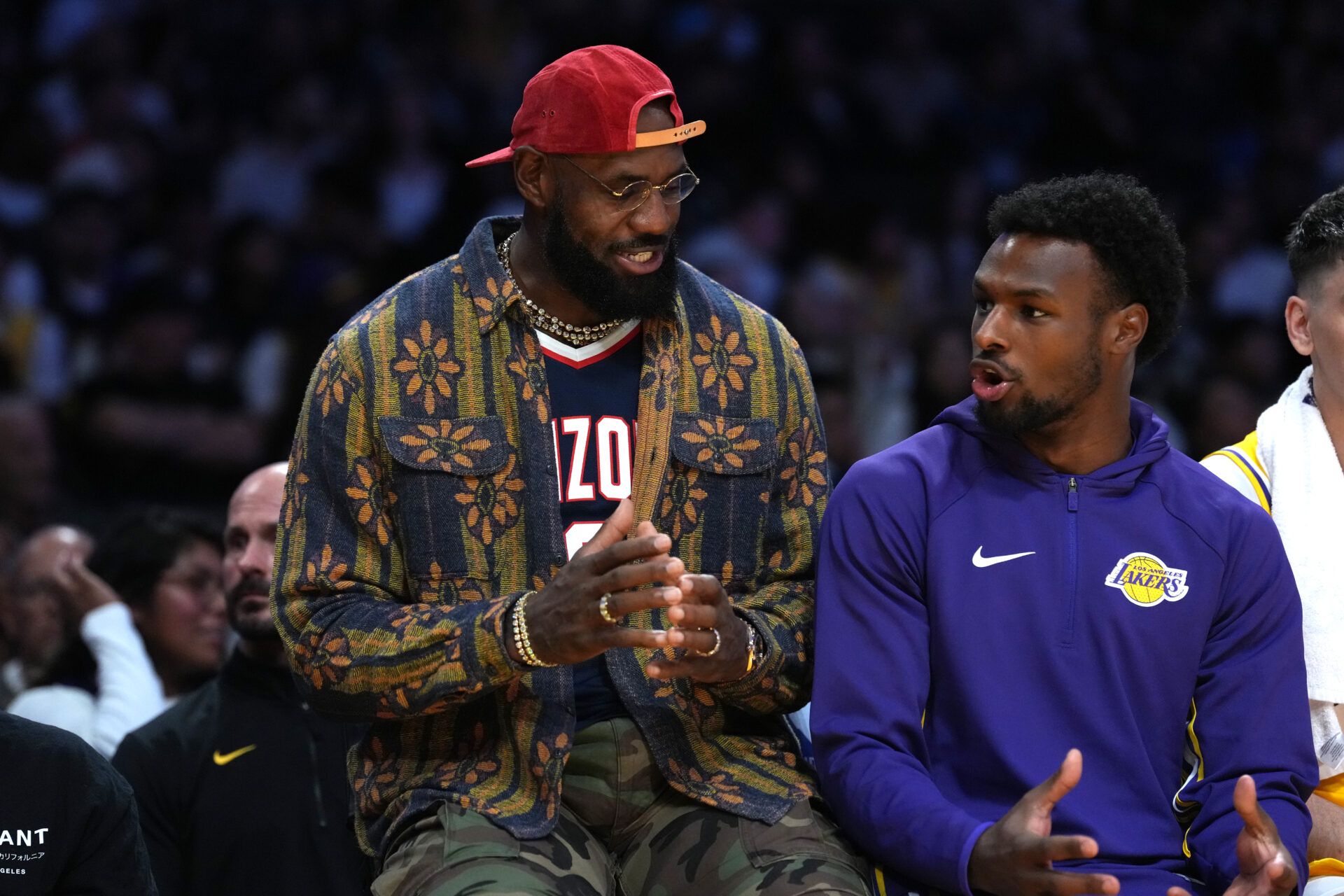 Los Angeles Lakers forward LeBron James (left) and son Bronny James  watch from the bench in the second half against the Minnesota Timberwolves at Crypto.com Arena.