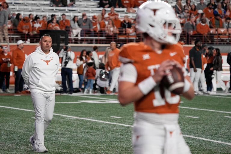 Texas Longhorns head coach Steve Sarkisian observes quarterback Arch Manning (16) warming up before a game against the Texas Tech Red Raiders at Darrell K Royal-Texas Memorial Stadium.