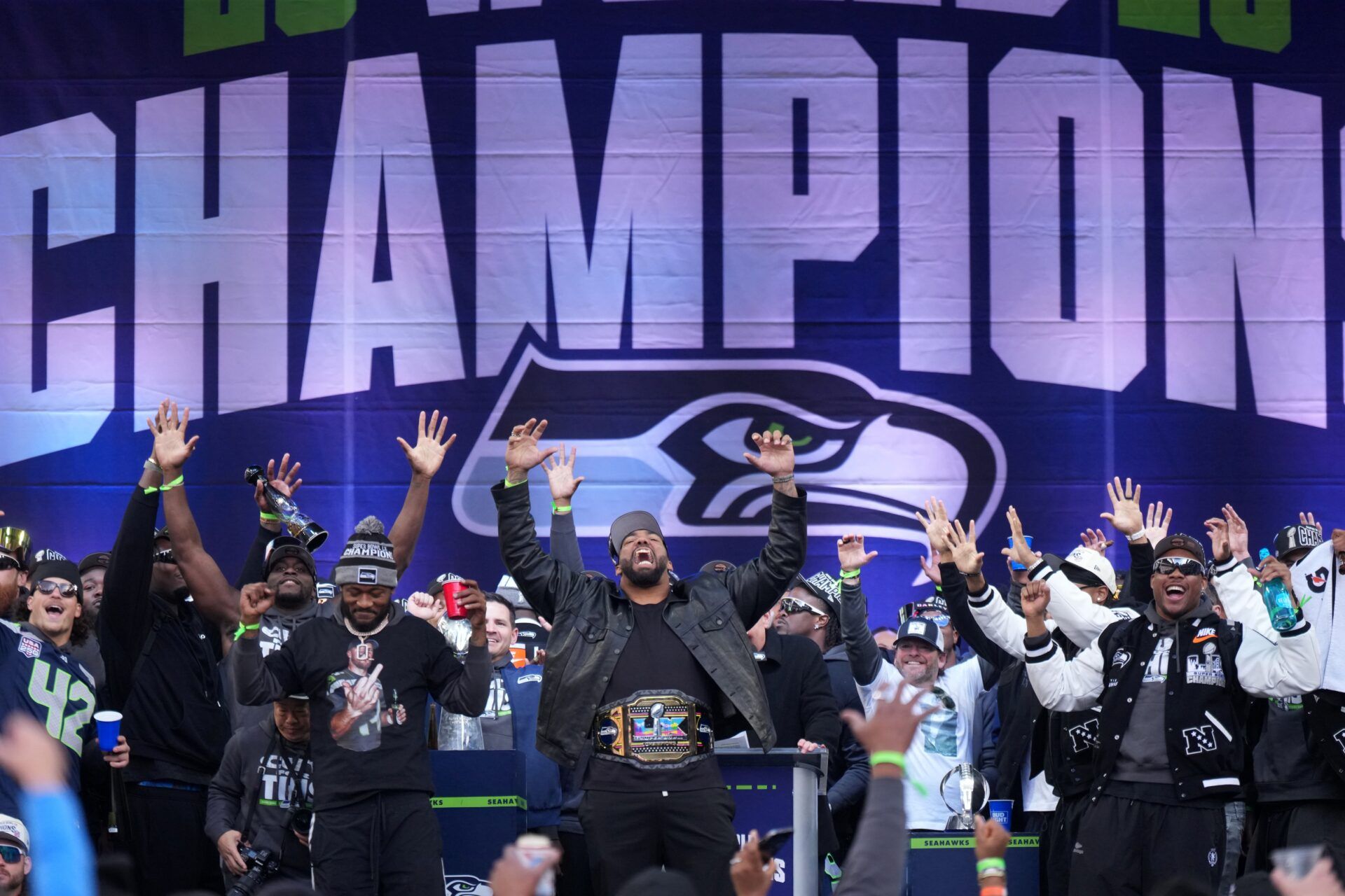 Seattle Seahawks linebacker Ernest Jones IV (left), defensive end Leonard Williams (center) and cornerback Devon Witherspoon (21) react during the Super Bowl LX trophy celebration at Lumen Field.