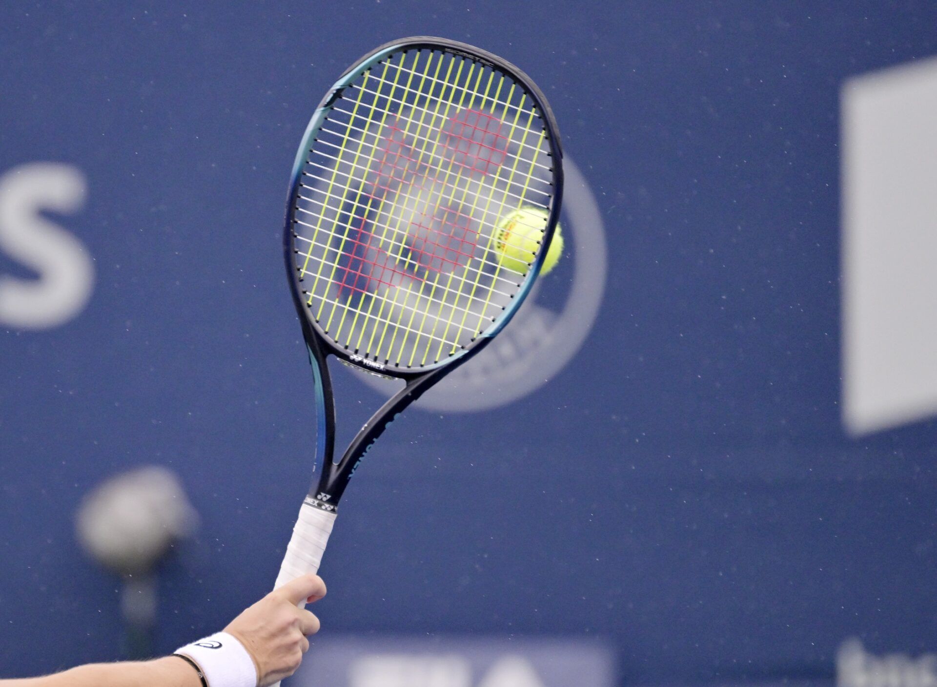 Racket and ball while the light rain starts in first round play at IGA Stadium.