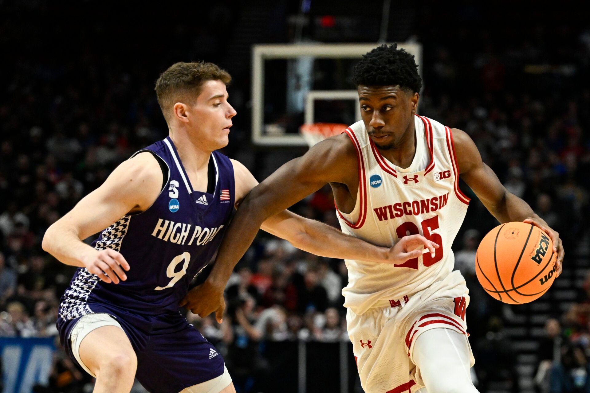 Wisconsin Badgers guard John Blackwell (25) drives against High Point Panthers guard Conrad Martinez (9) during the second half of a first round game of the men's 2026 NCAA Tournament at Moda Center.