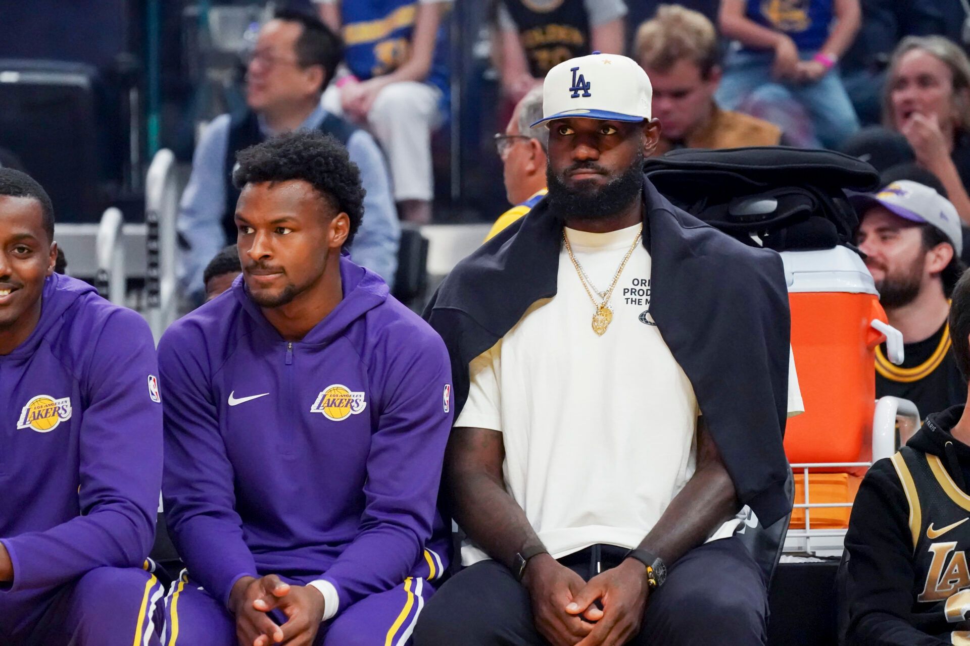 Los Angeles Lakers guard Bronny James (9) and forward LeBron James (23), wearing a Los Angeles Dodgers cap, watch the action against the Golden State Warriors in the first quarter at Chase Center.