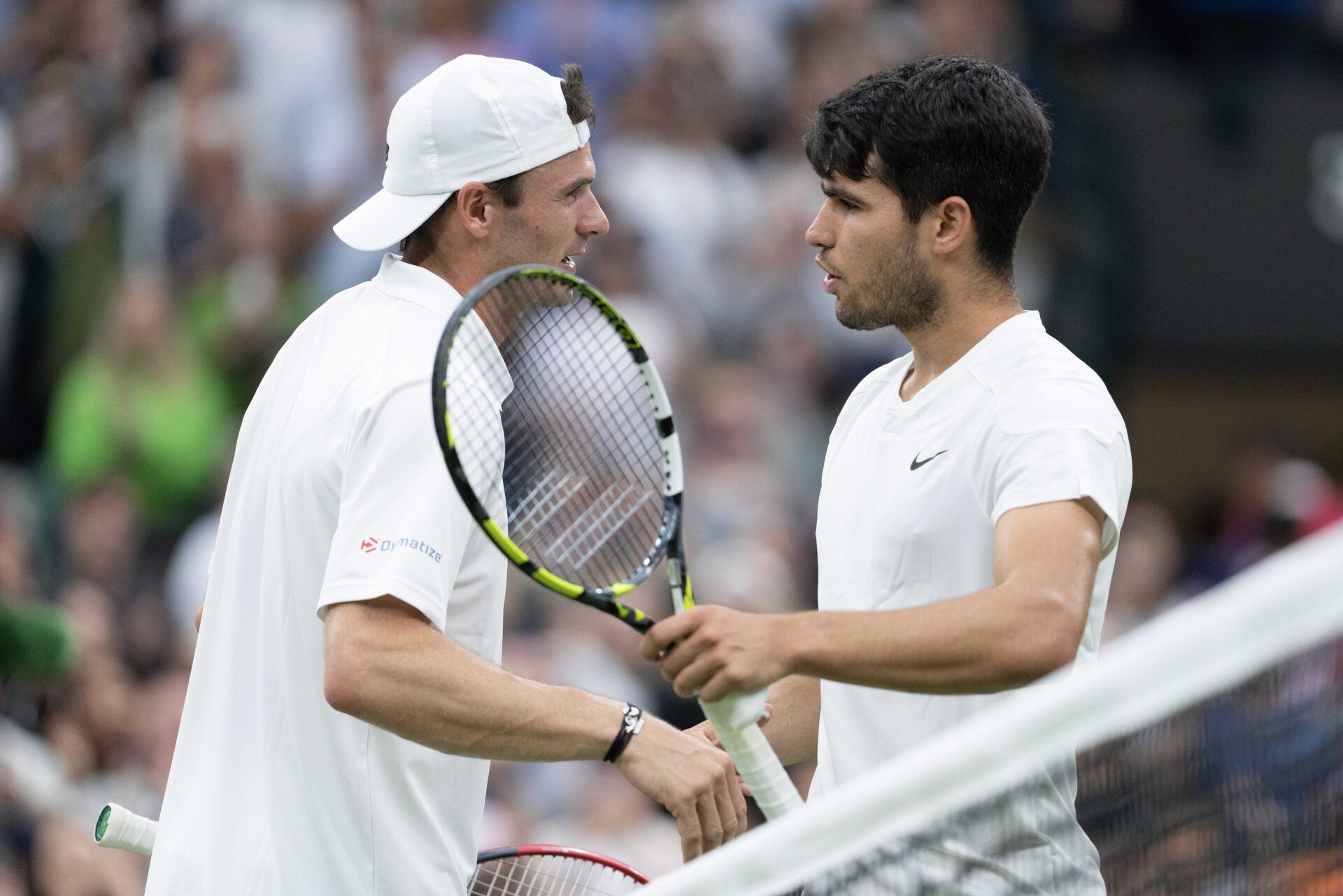 Carlos Alcaraz of Spain at the net with Tommy Paul of the United States after their match on day nine of The Championships at All England Lawn Tennis and Croquet Club.