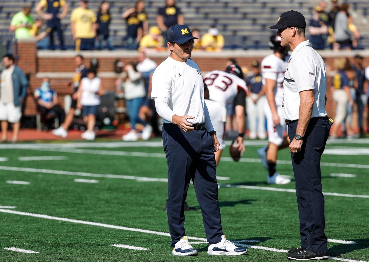 Michigan defensive coordinator Mike Macdonald, left, talks to head coach Jim Harbaugh during warmups before a game against Northern Illinois at Michigan Stadium in Ann Arbor on Saturday, Sept. 18, 2021.