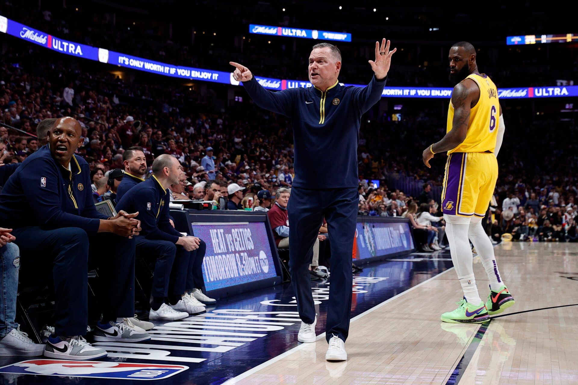 Denver Nuggets head coach Michael Malone signals as Los Angeles Lakers forward LeBron James (6) looks on in the first quarter during game one of the Western Conference Finals for the 2023 NBA playoffs at Ball Arena.