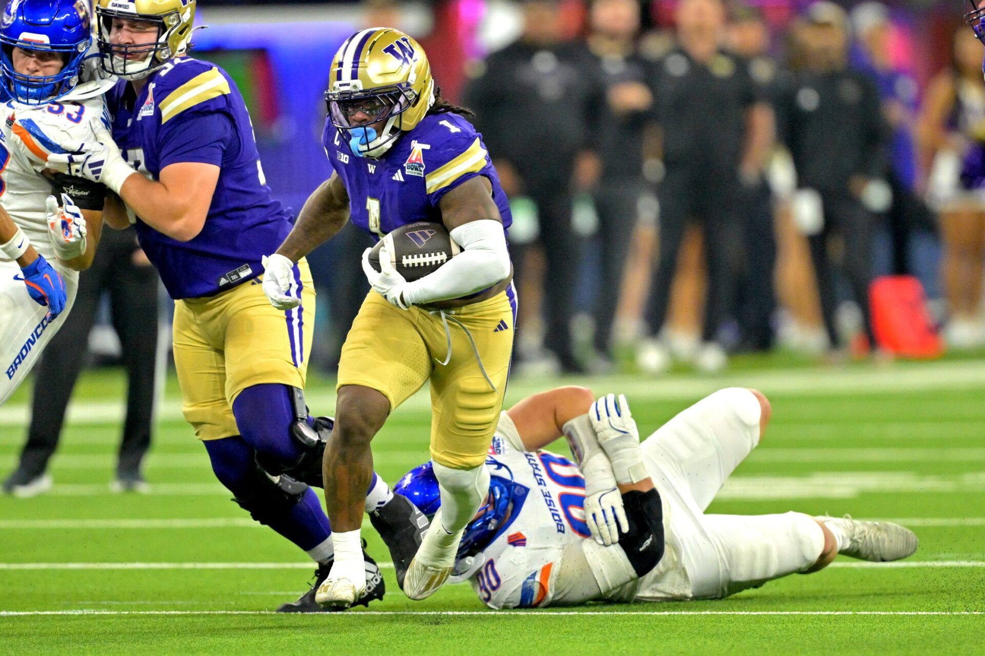 Washington Huskies running back Jonah Coleman (1) carries past Boise State Broncos wide receiver Cameron Bates (80) for a first down in the first half of the LA Bowl at SoFi Stadium.