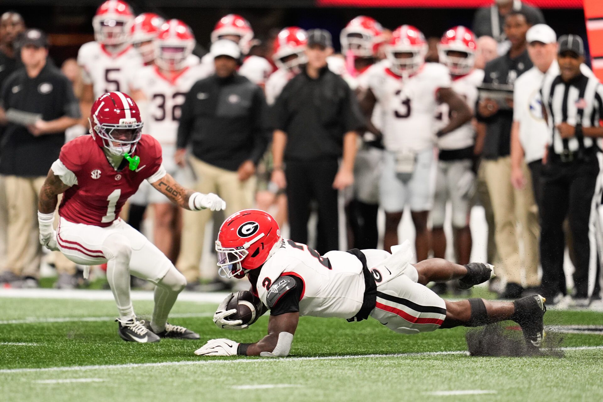 Georgia Bulldogs running back Josh McCray (2) trips while rushing as Alabama Crimson Tide defensive back Domani Jackson (1) defends during the first quarter during the 2025 SEC Championship game at Mercedes-Benz Stadium.