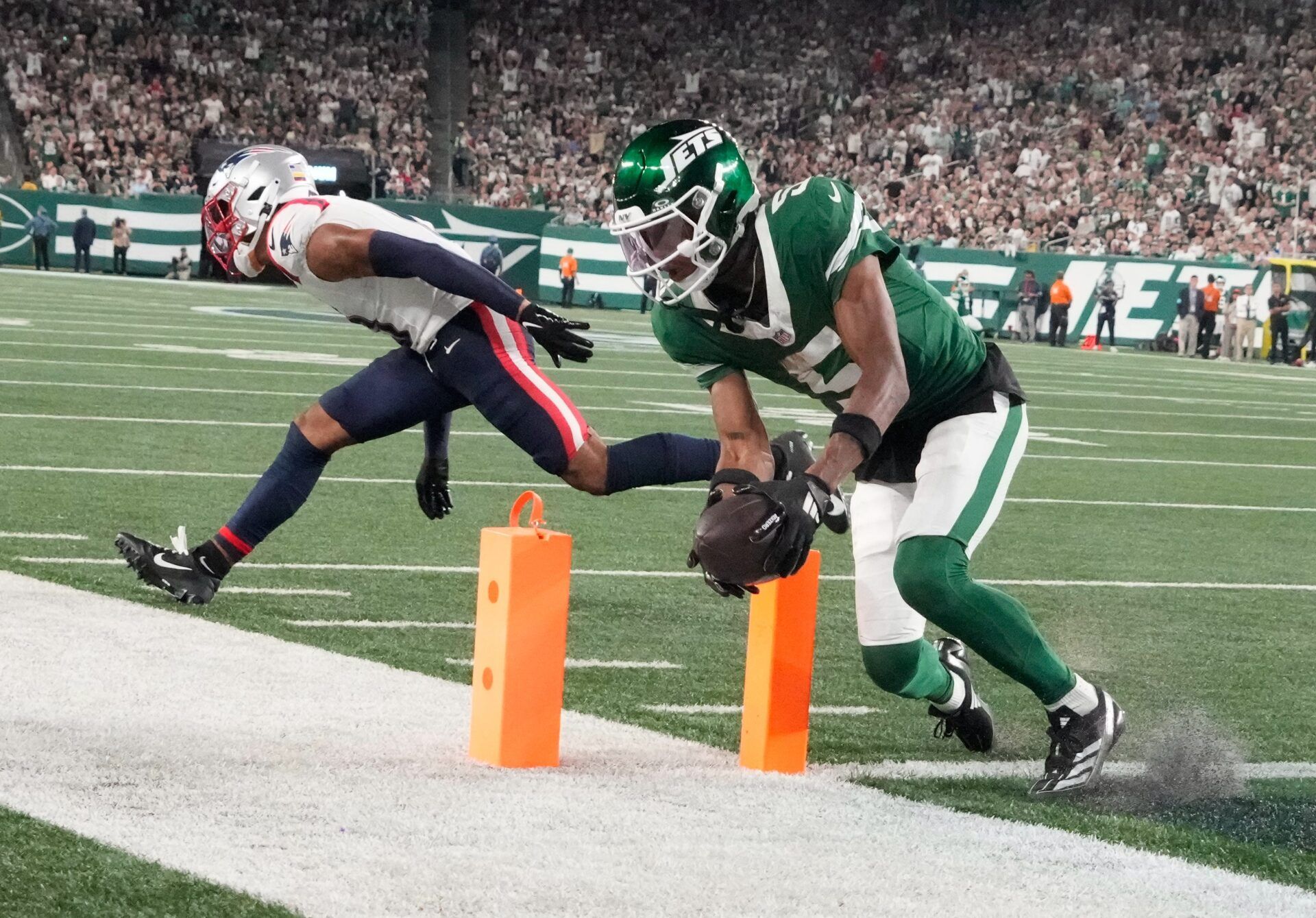 New York Jets wide receiver Garrett Wilson (5) scores a 3rd quarter touchdown in front of New England Patriots cornerback Christian Gonzalez (0) at MetLife Stadium.