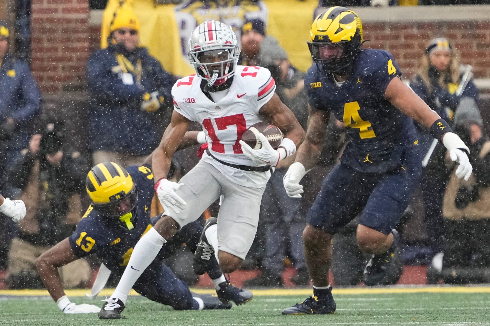 Ohio State Buckeyes wide receiver Carnell Tate (17) runs past Michigan Wolverines defensive back Caleb Anderson (13) and defensive end T.J. Guy (4) during the NCAA football game at Michigan Stadium in Ann Arbor, Mich. on Nov. 29, 2025. Ohio State won 27-9.